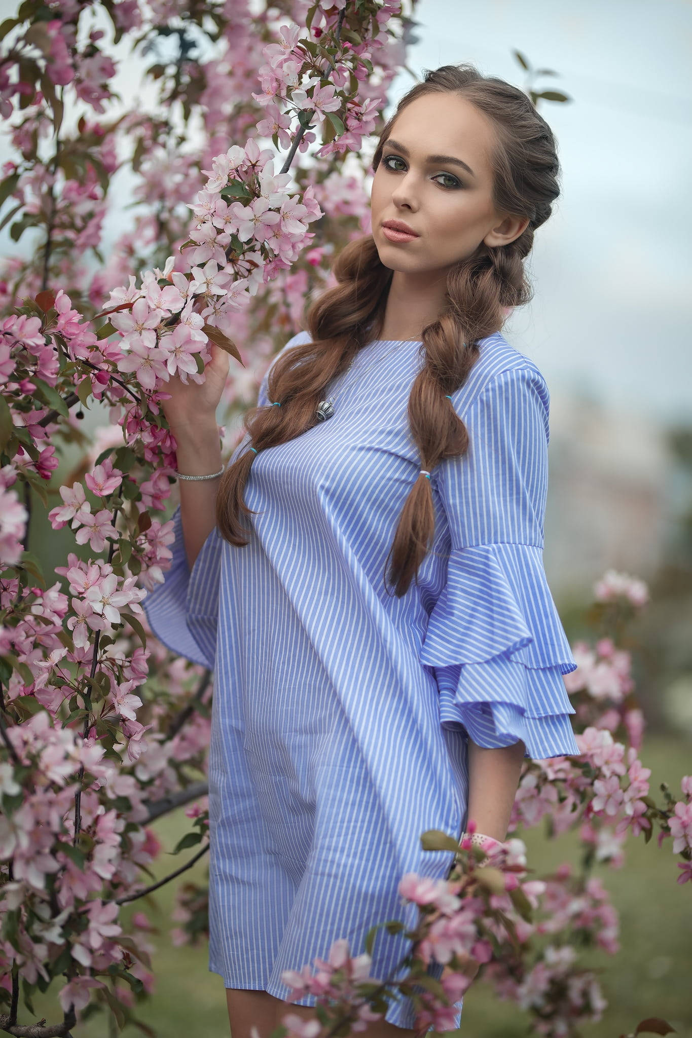 Beautiful Girl 桌布 壁紙 — 一位身穿藍色條紋連衣裙的年輕女子在柔和春日裡優雅地站在盛開的粉紅色櫻花中。