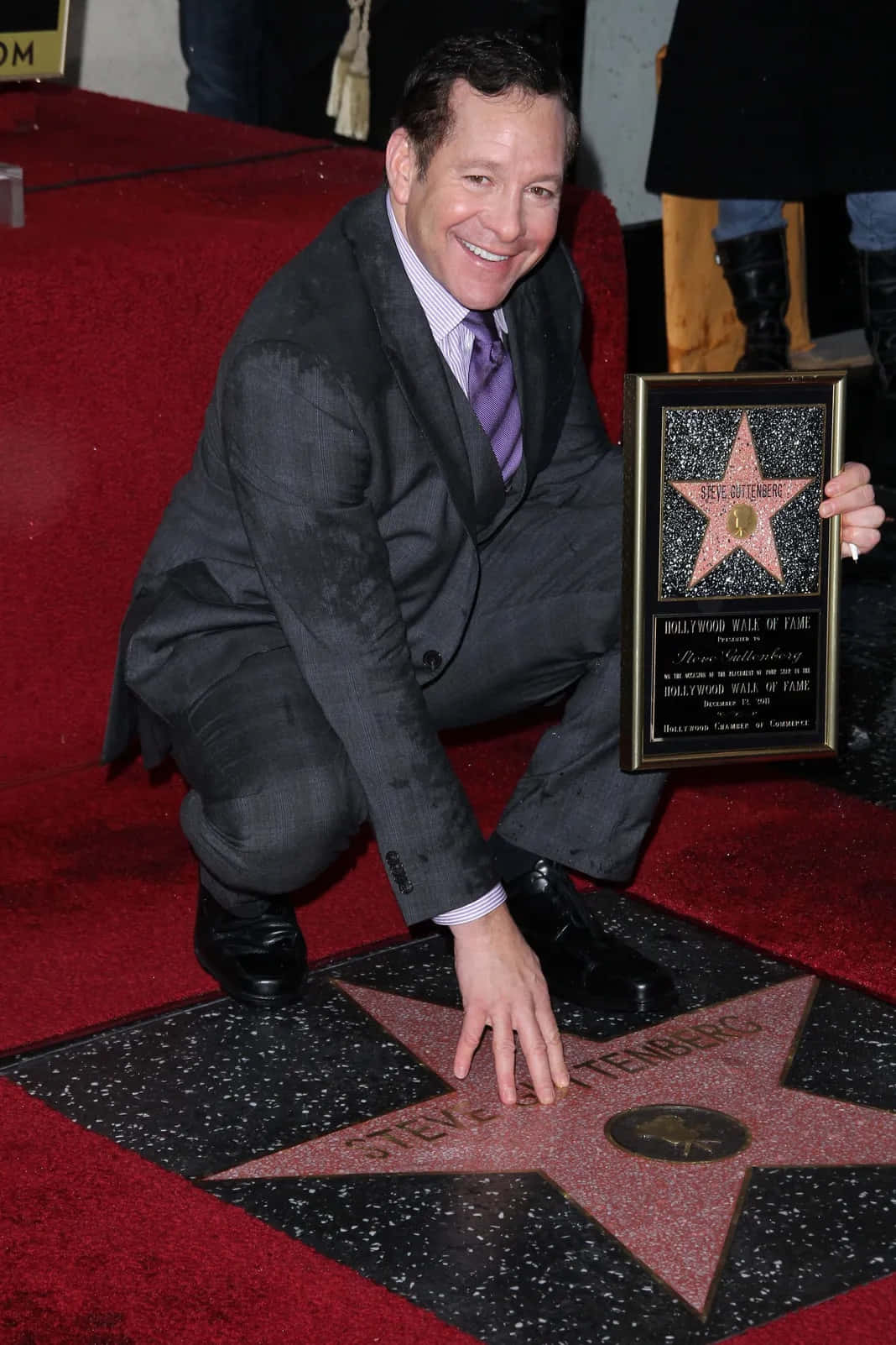 Steve Guttenberg 桌布 壁紙 — 一位身穿西裝、面帶微笑的男子跪在荷里活星光大道星星旁的紅地毯上，手持紀念牌匾。
