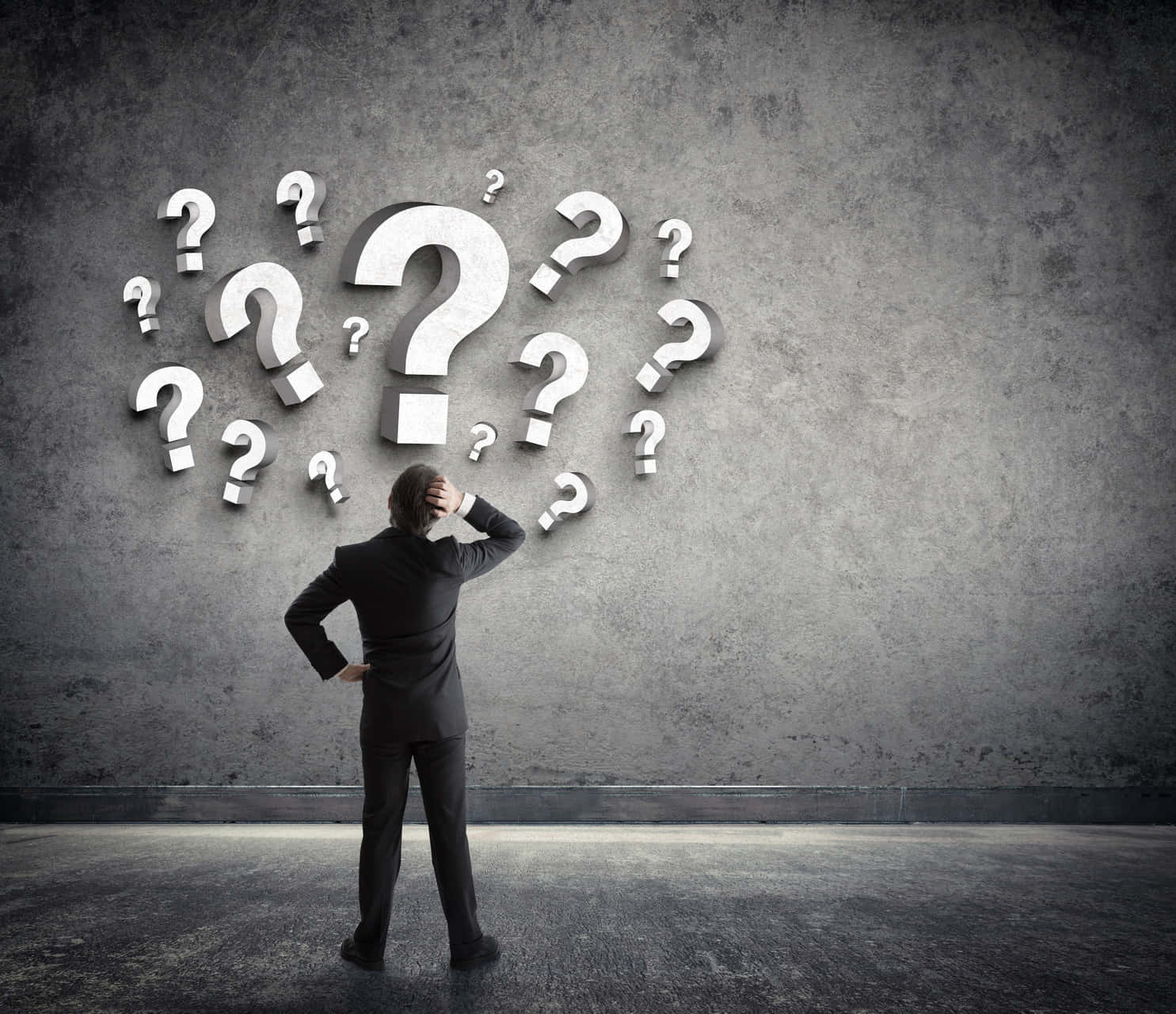 Thinking 桌布 壁紙 — 一位身穿西裝的商人手放在頭上，凝視著一面佈滿漂浮3D問號的牆壁。