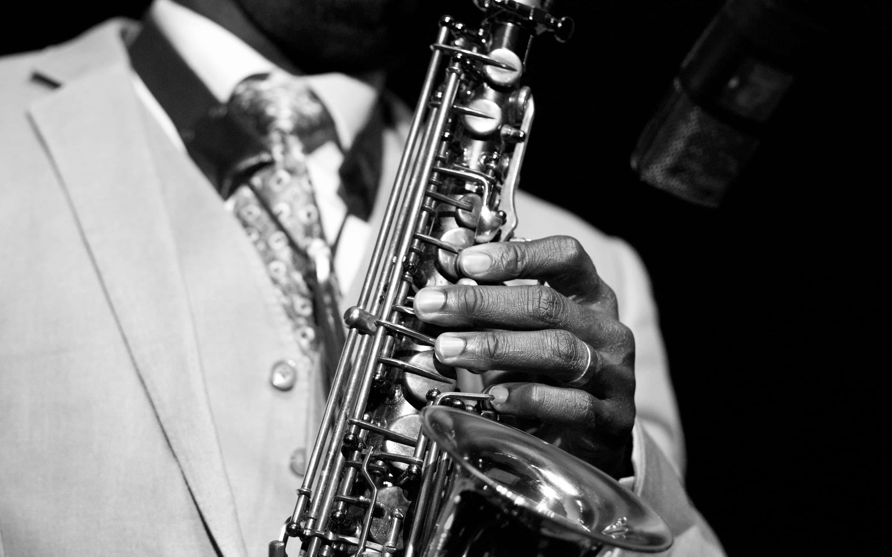 Jazz 桌布 壁紙 — 一位身穿西裝的音樂家在戲劇性的黑白燈光下吹奏色士風，附近有一個咪高峰。