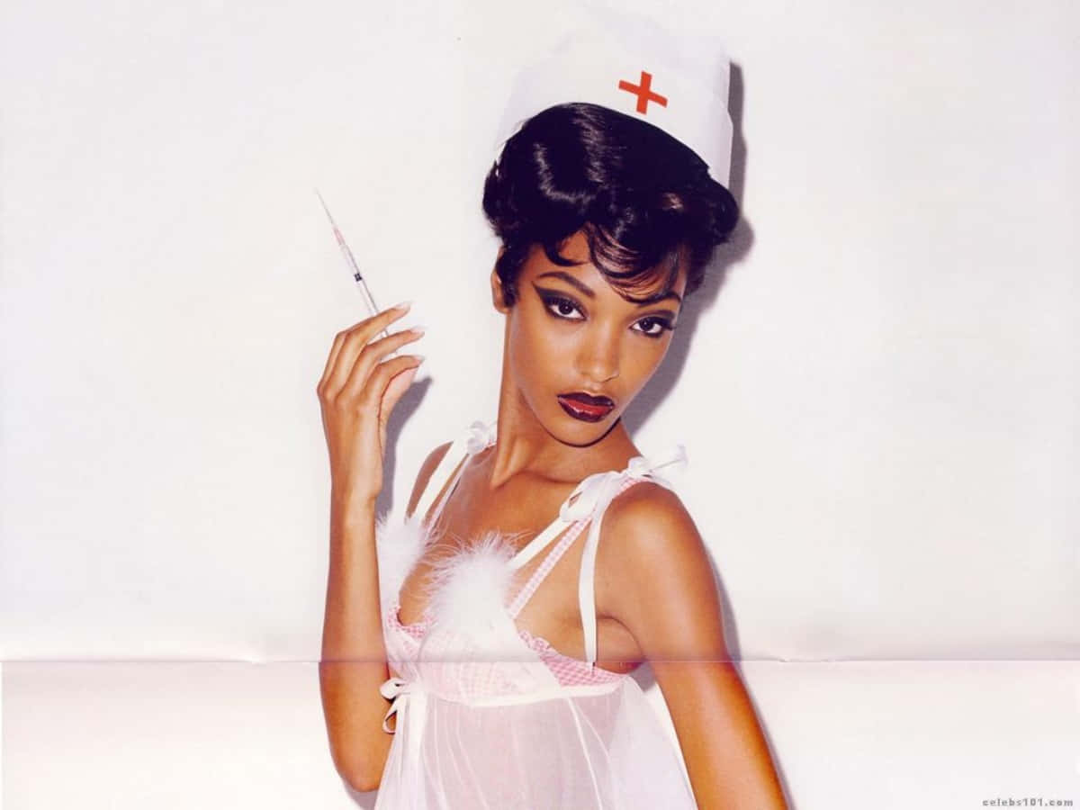 jourdan dunn 桌布 壁紙 — 一位身穿護士服、戴著紅十字帽子的女性，在純白背景下拿著注射器。