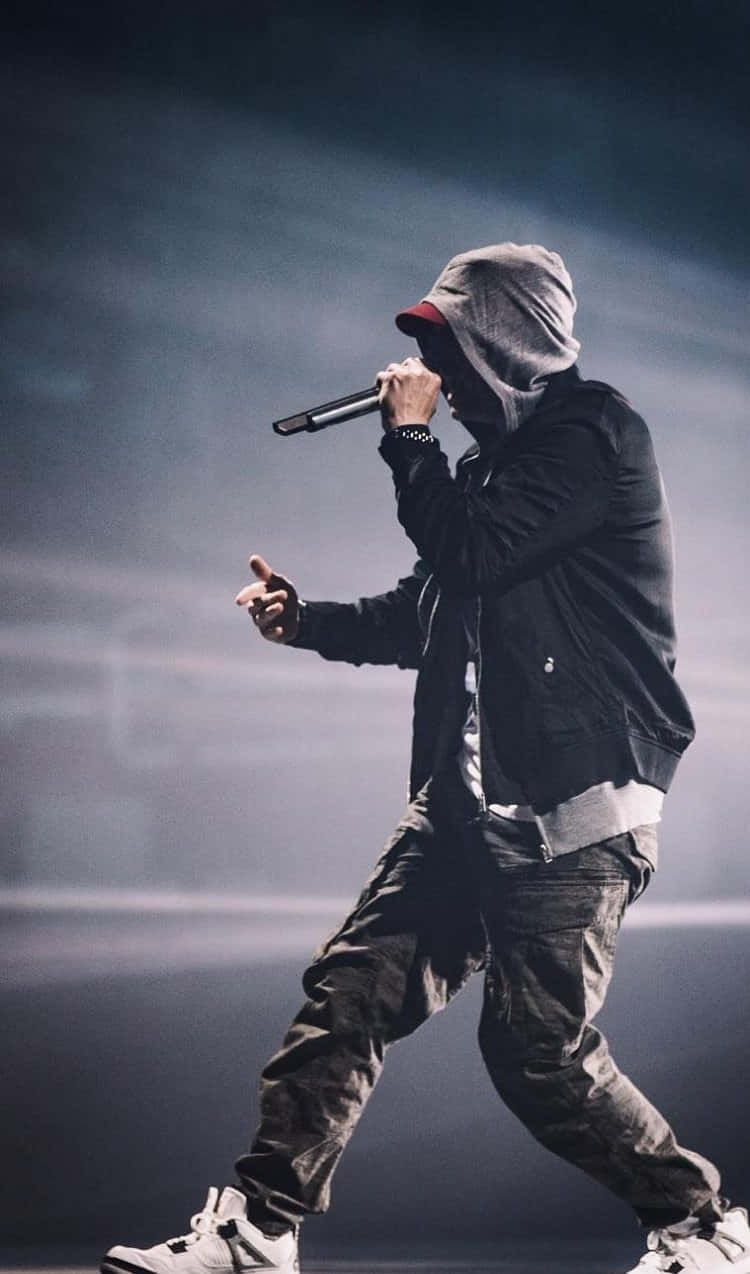 Drake 桌布 壁紙 — 一位身穿連帽衫和帽子的說唱歌手在煙霧彌漫的舞台上，在戲劇性的燈光下激情表演。