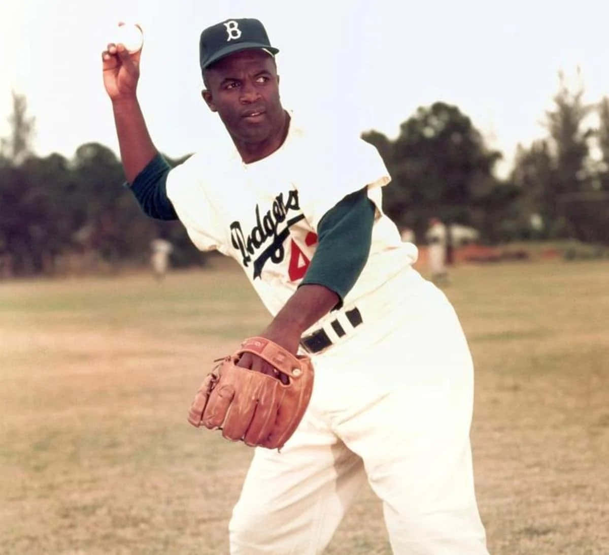 Jackie Robinson 桌布 壁紙 — 一位身穿道奇隊制服的黑人棒球運動員在陽光明媚的球場上專注投球。