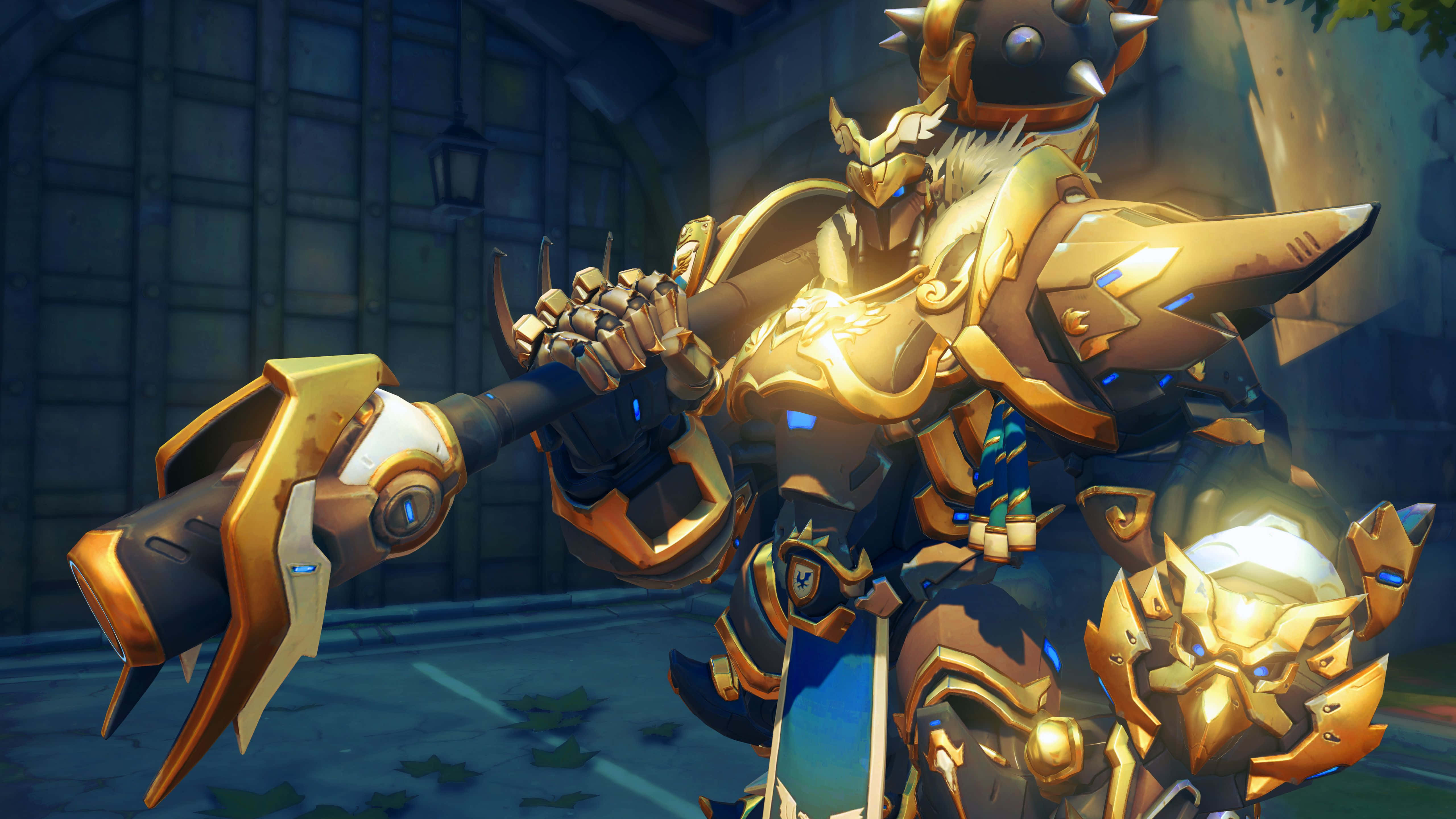 Overwatch Reinhardt 桌布 壁紙 — 一位身穿金色盔甲、帶有藍色光芒的戰士，在昏暗的城市小巷中揮舞著一把巨大的錘子。