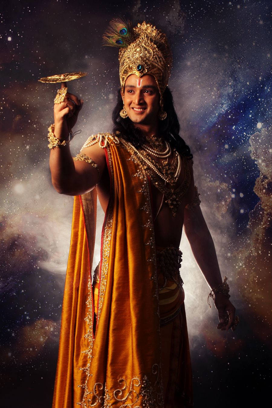 krishna iPhone 桌布 壁紙 — 一位身穿金色華服的光輝神祇，在宇宙星空背景下手持發光的圓盤。
