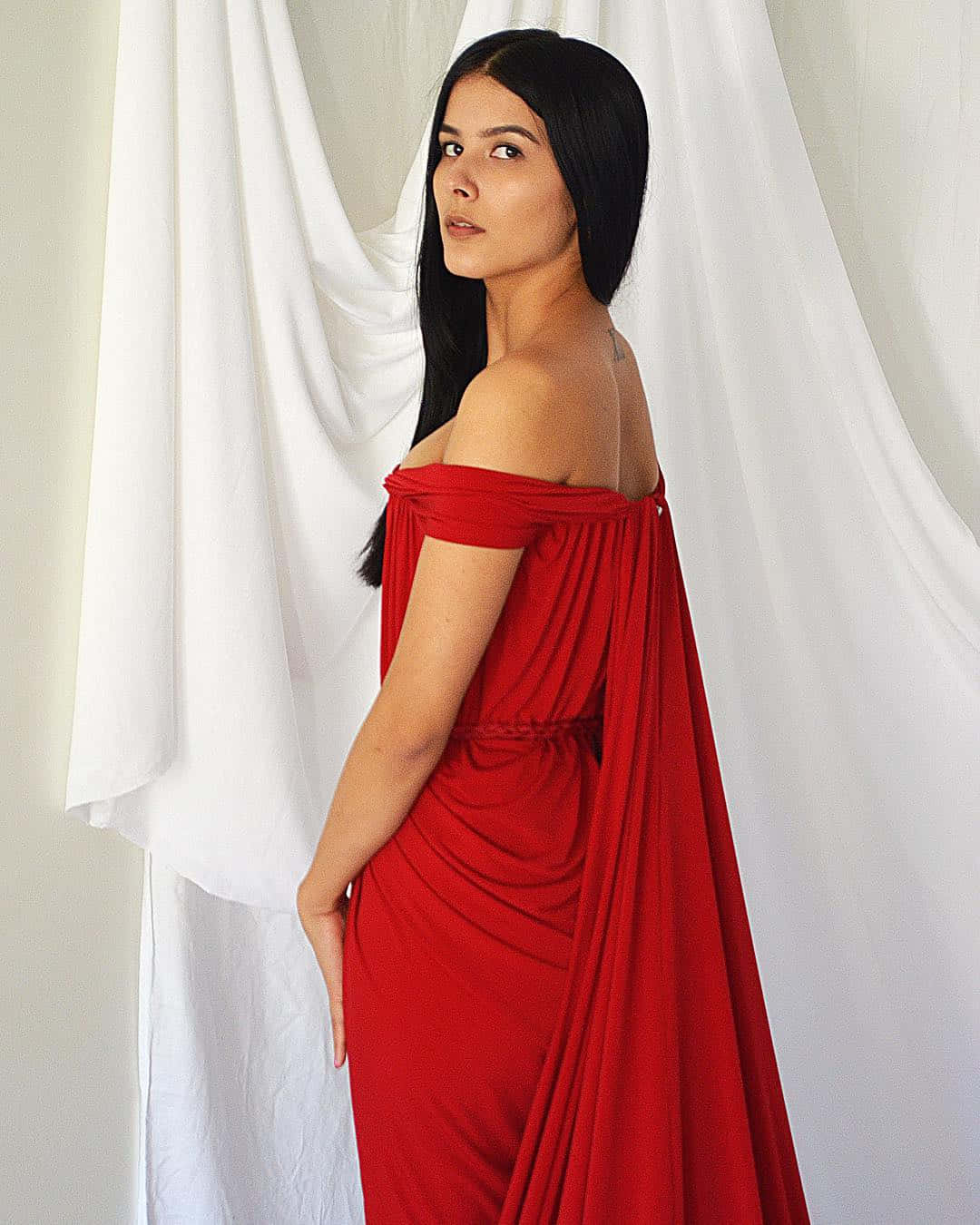 Red Clothing 桌布 壁紙 — 一位身穿飄逸紅色露肩長裙的女性，在白色垂簾前以從容的表情優雅站立。