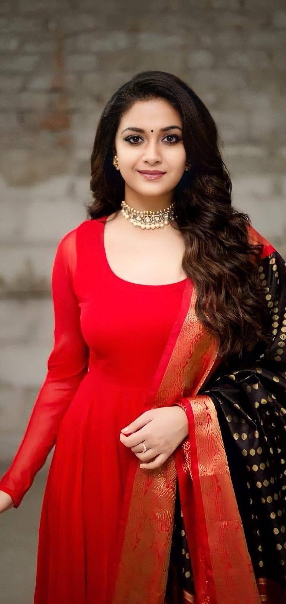Tamil Actors HD 桌布 壁紙 — 一位身穿鮮紅色連衣裙和黑金色杜帕塔的女性，在紋理石牆前優雅地擺姿勢。