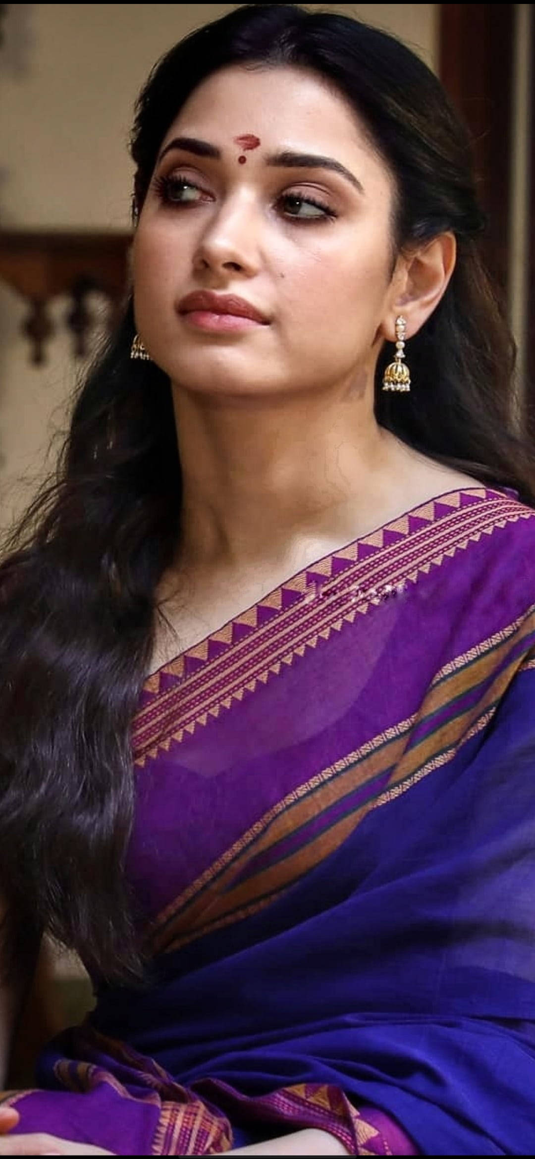 Indian 桌布 壁紙 — 一位身穿鮮豔紫色和金色圖案紗麗的女性，長長的黑髮和傳統珠寶，若有所思地向上凝視。