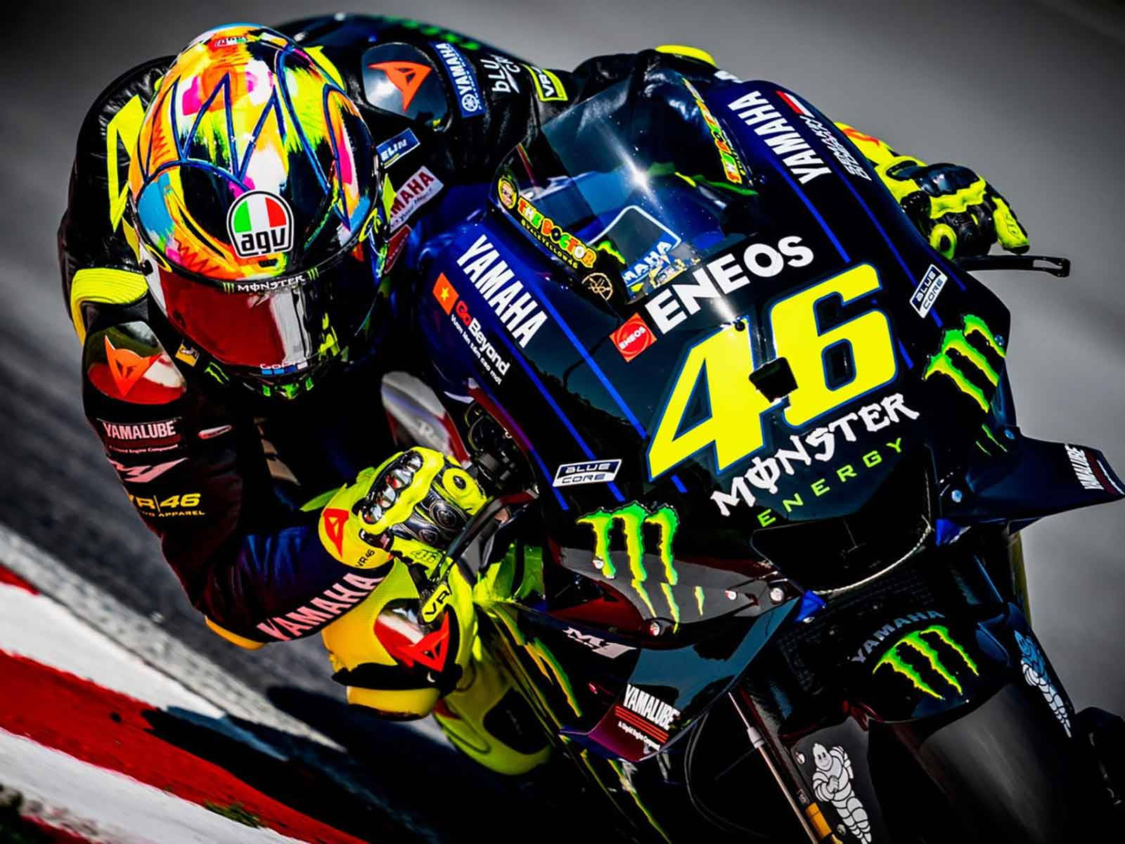 Monster Energy 桌布 壁紙 — 一位身穿鮮豔裝備的電單車賽車手，在飾有Monster Energy標誌的流線型Yamaha電單車上傾斜入彎。