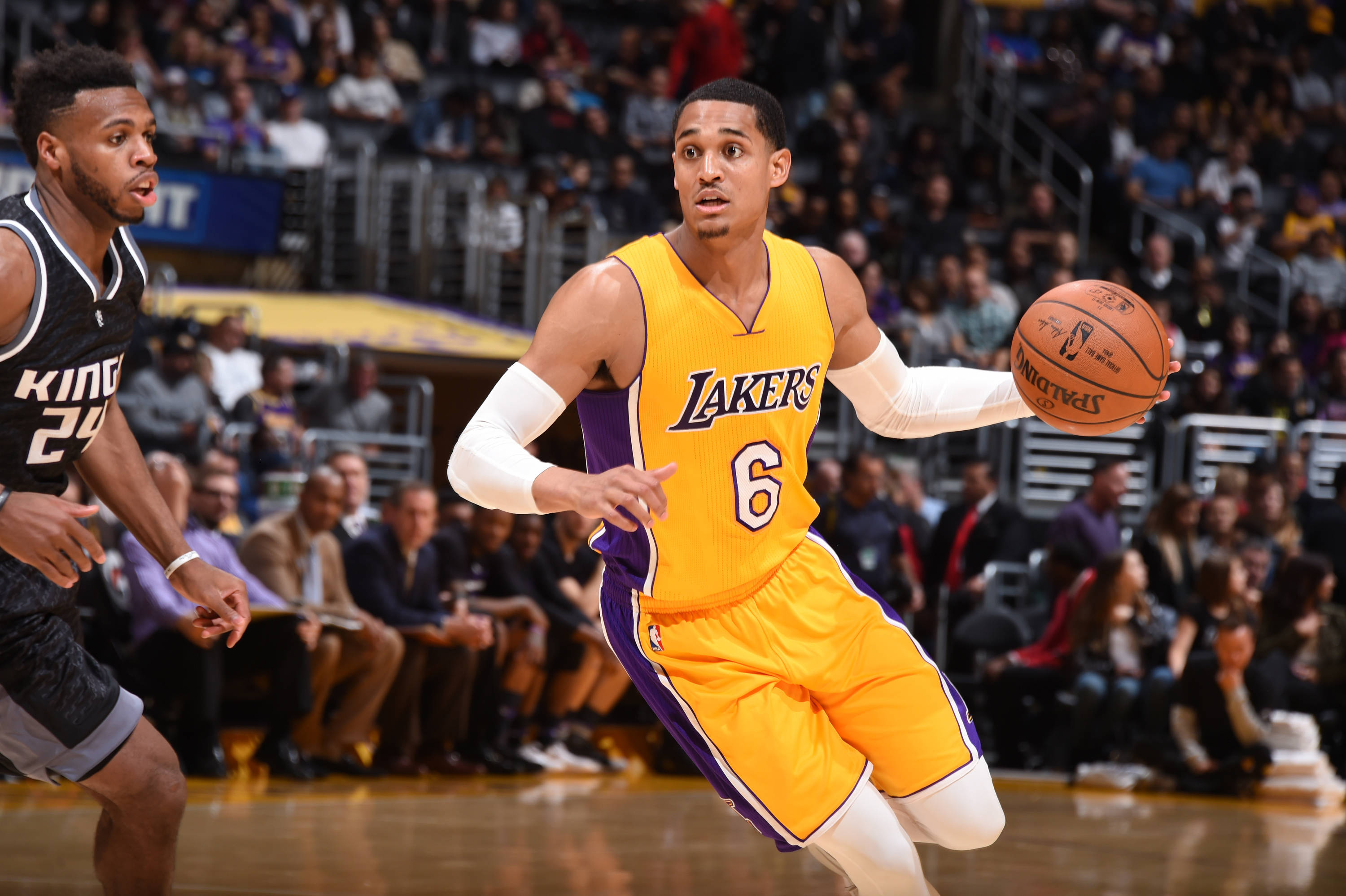 NBA Jordan Clarkson 壁紙 — 一位身穿黃色和紫色球衣的洛杉磯湖人球員在激烈的NBA比賽中運球，同時被薩克拉門托國王隊的球員防守。