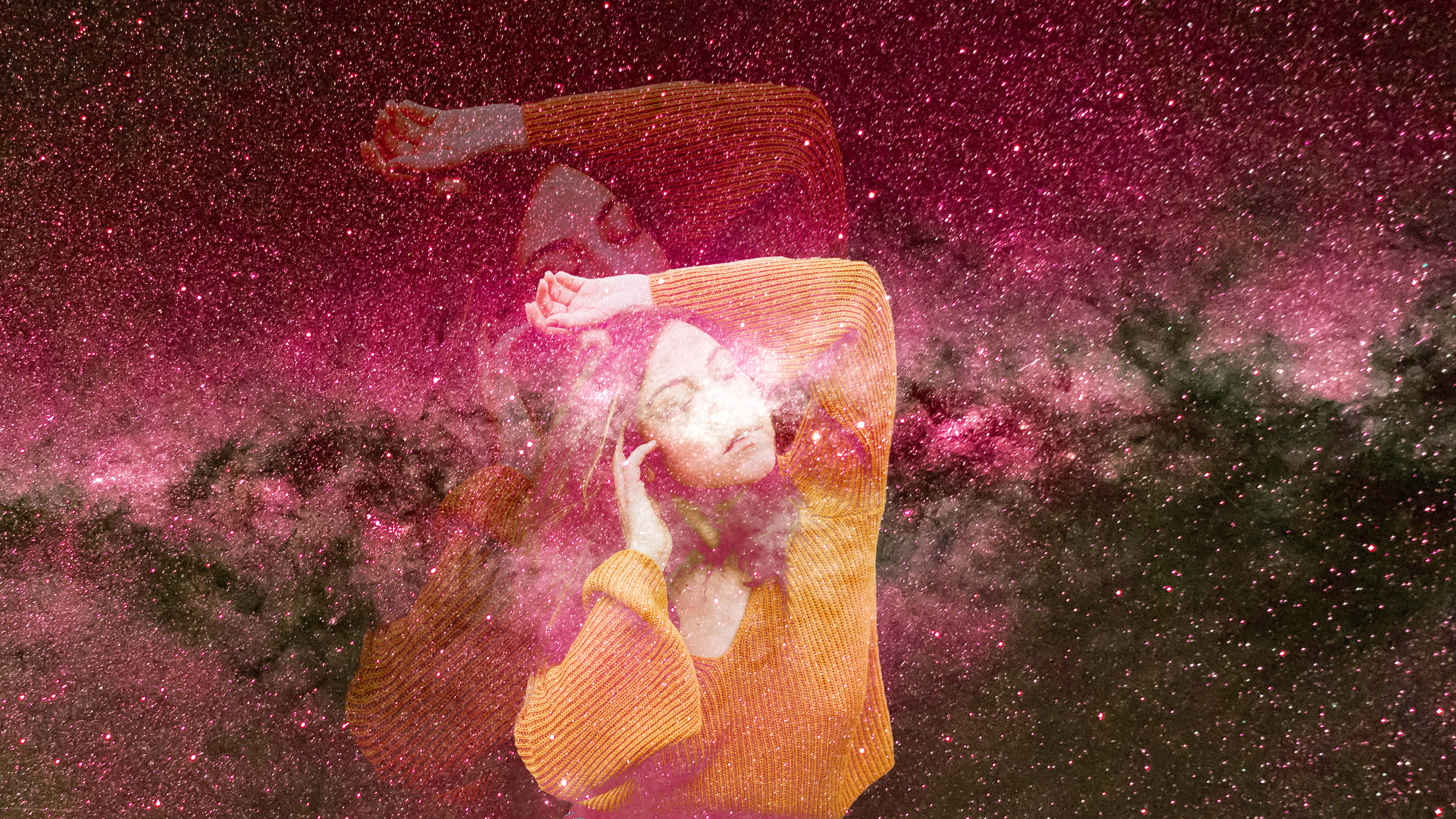 銀河 桌布 壁紙 — 一位身穿黃色毛衣的女性漂浮在充滿旋轉星雲和星星的鮮豔粉紅色宇宙天空中。