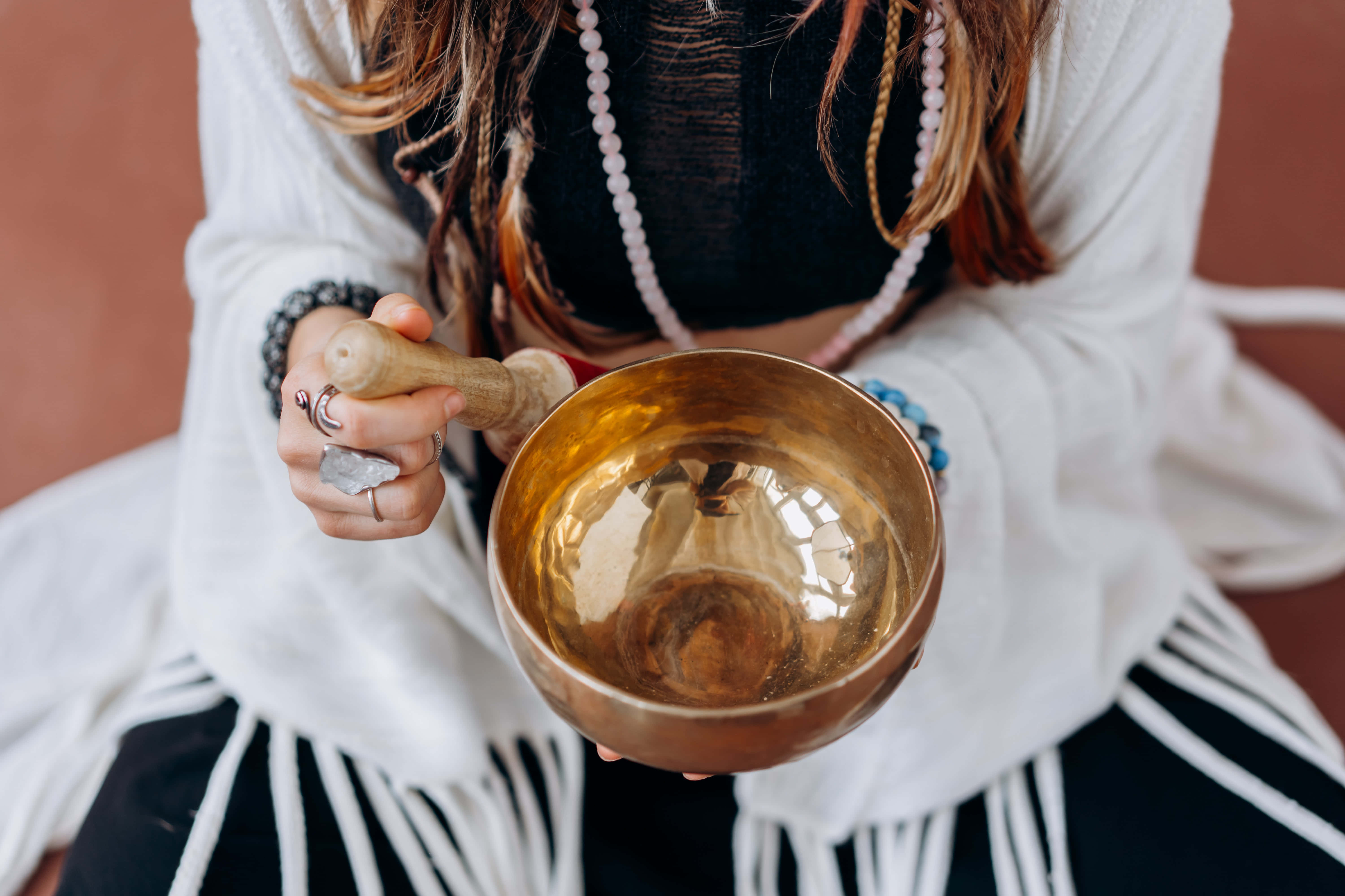 Reiki 桌布 壁紙 — 一位身穿黑白波希米亞服飾的人手持金色頌缽和木槌，準備演奏。