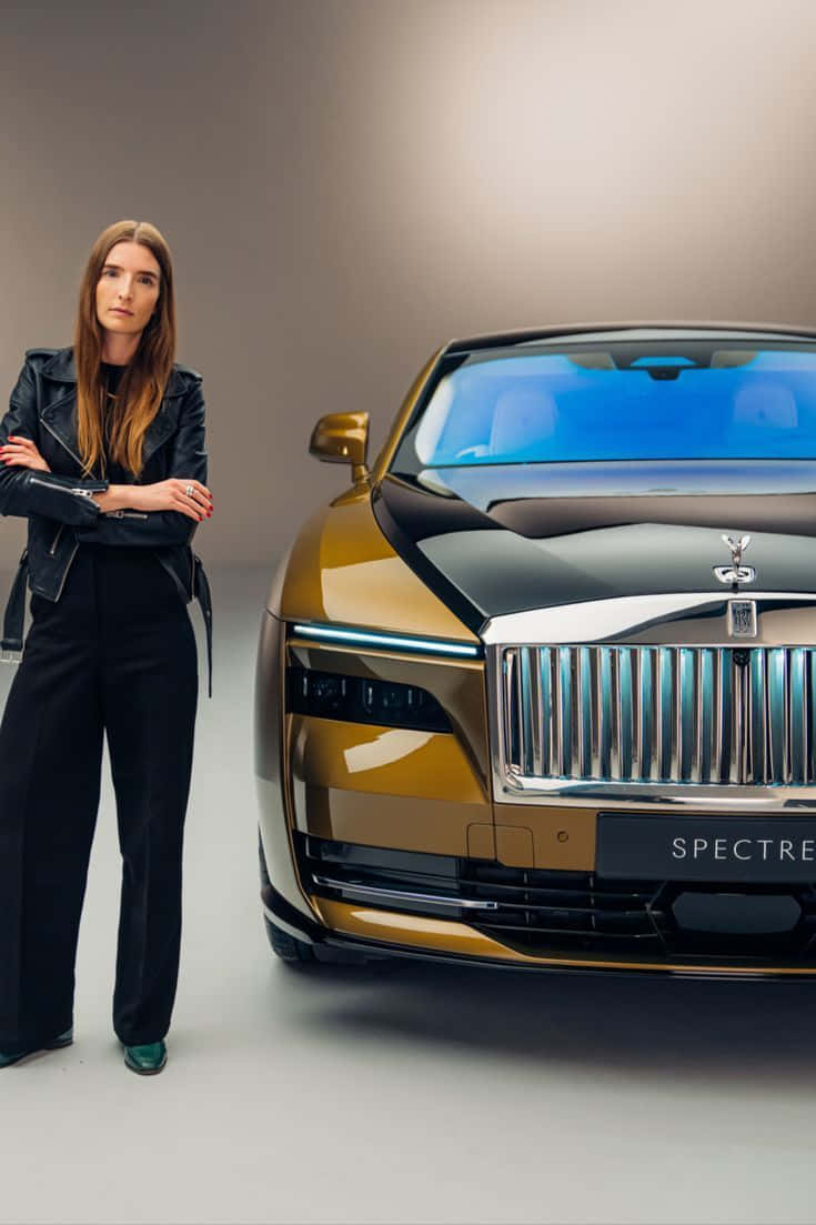 Rolls Royce Camargue 桌布 壁紙 — 一位身穿黑色皮革的優雅女性，在極簡風格的攝影棚中，站在一輛金色和黑色的勞斯萊斯 Spectre 旁邊。