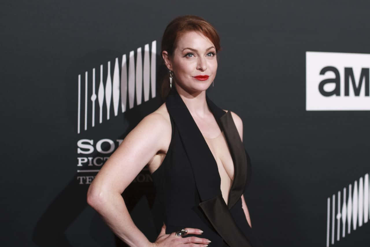 Esmé Bianco 桌布 壁紙 — 一位身穿黑色連衣裙的優雅女性在紅地毯活動上自信地擺姿勢，背景是 'Sony Pictures Television' 品牌標誌。