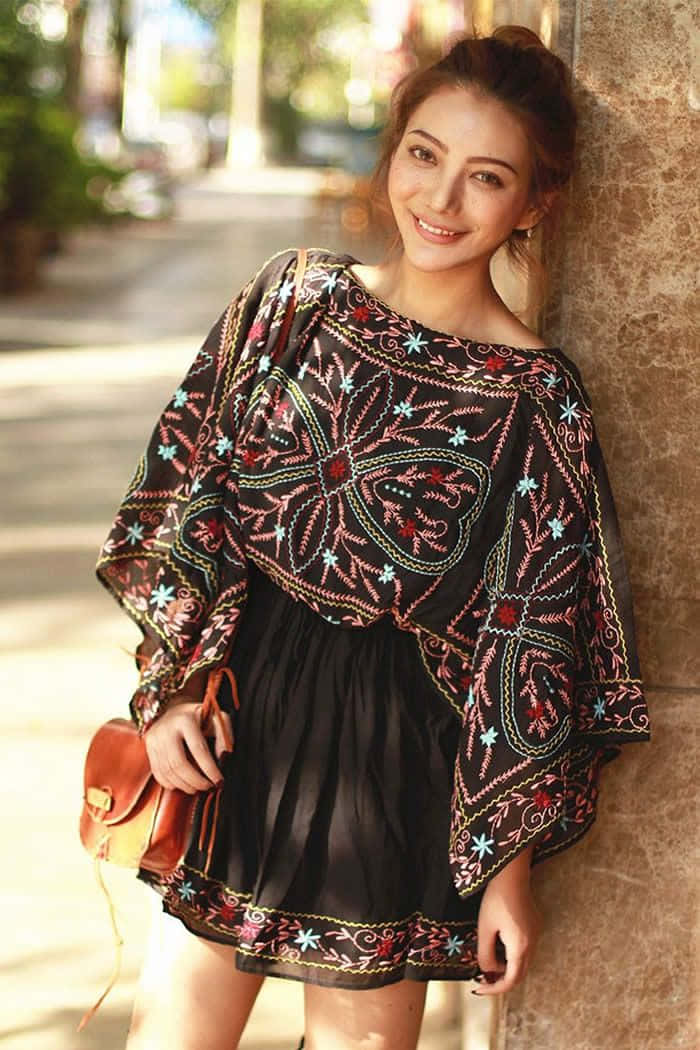 一位身穿黑色連身裙、手挽手袋的女性 壁紙