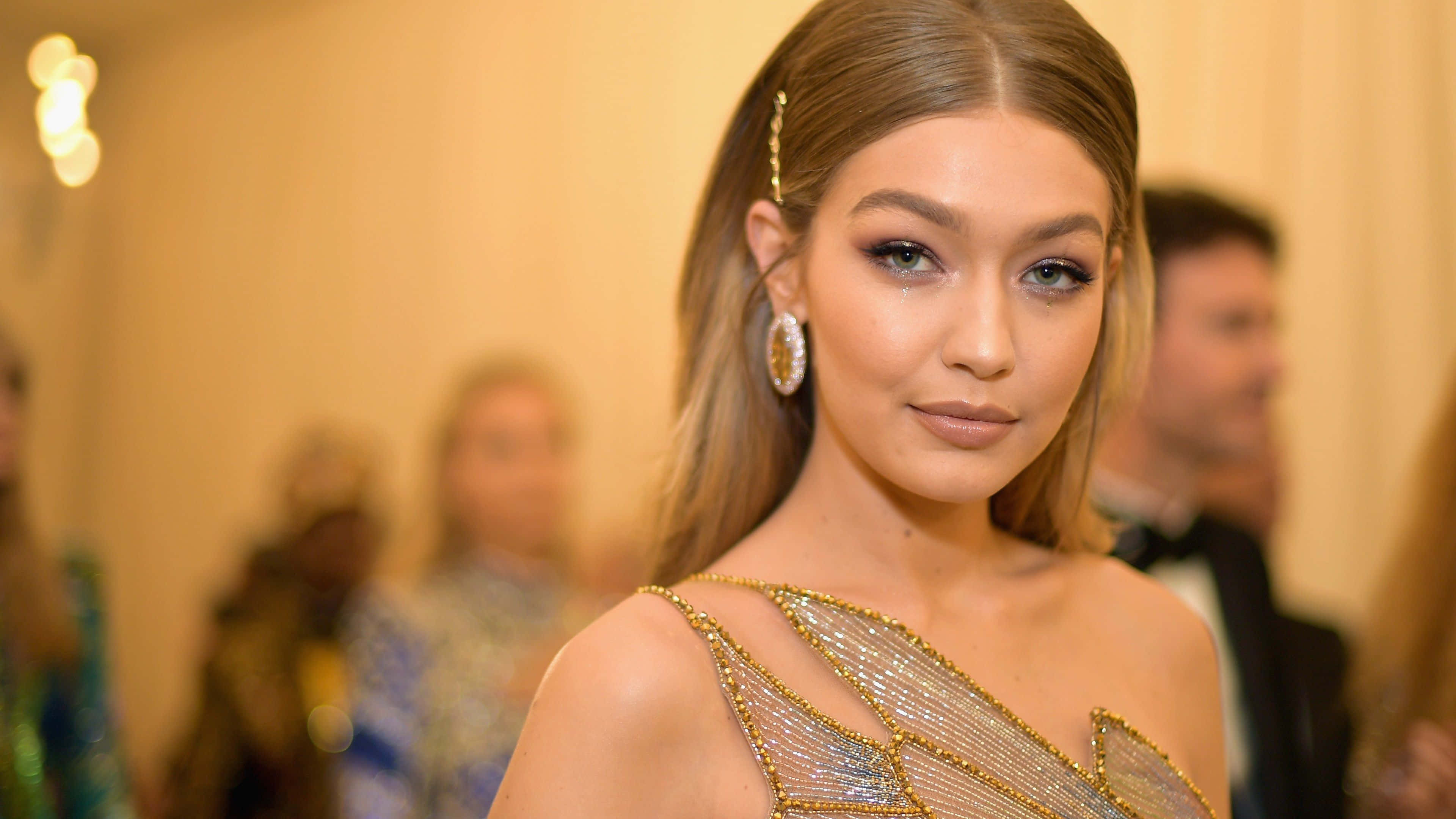 Met Gala 桌布 壁紙 — 一位迷人嘅女士穿著閃閃發光嘅金色珠片長裙，喺正式活動中自信地擺姿勢。