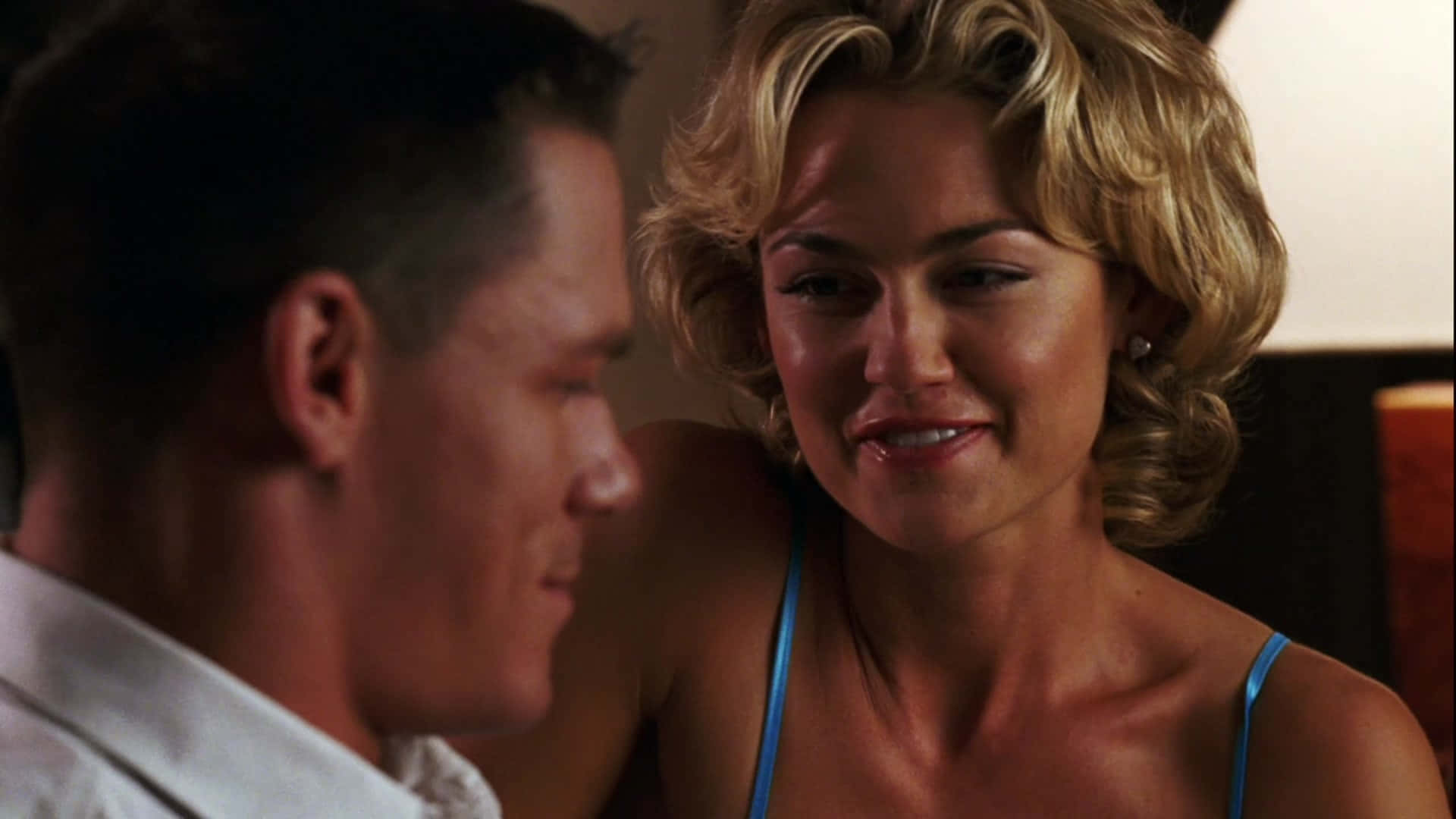 Kelly Carlson 桌布 壁紙 — 一位金色捲髮的女性在昏暗的房間裡對一位男士溫暖地微笑，營造出親密浪漫的氛圍。
