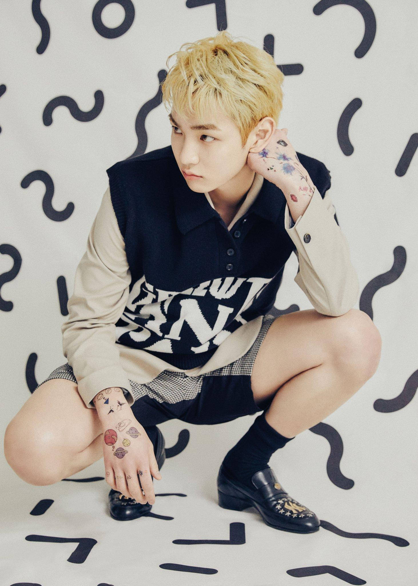 Shinee Key I Wanna Be 壁紙 — 一位金髮、身上有彩色紋身的年輕男子蹲在白色牆壁前，牆上有黑色抽象塗鴉。