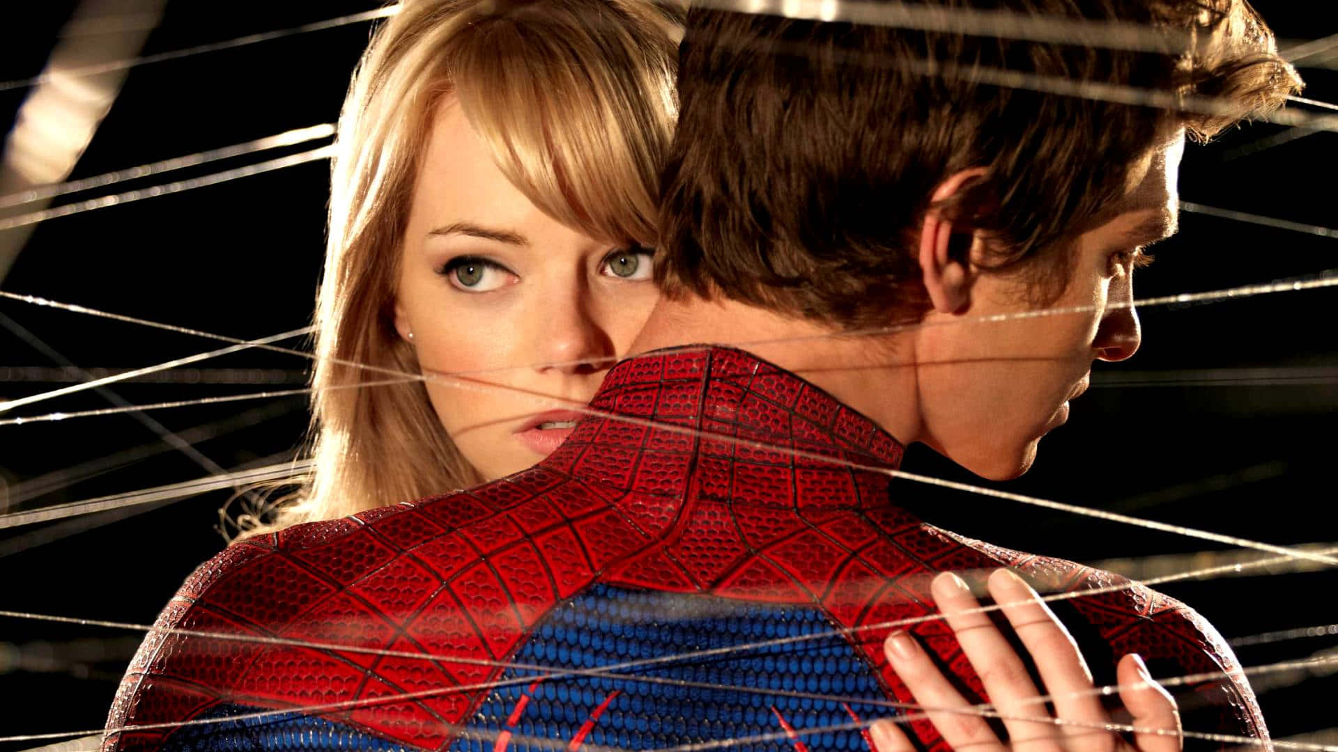 Gwen Stacy 桌布 壁紙 — 一位金髮女子在蜘蛛網交錯的黑暗背景前，專注地越過蜘蛛俠的肩膀凝視。