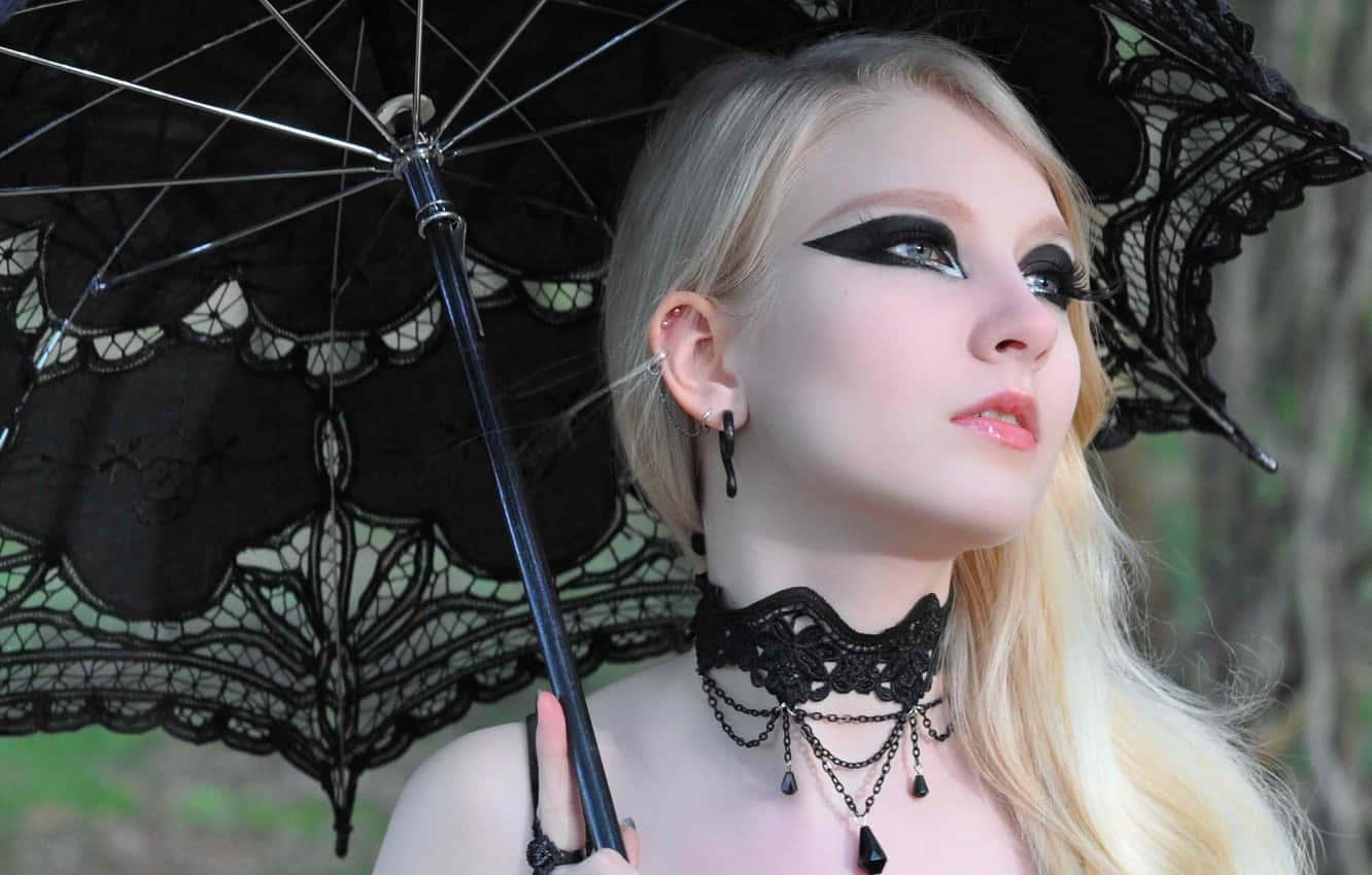 Gothic Fashion 桌布 壁紙 — 一位金髮女子畫著戲劇性的黑色眼線，在森林環境中手持一把黑色蕾絲陽傘。