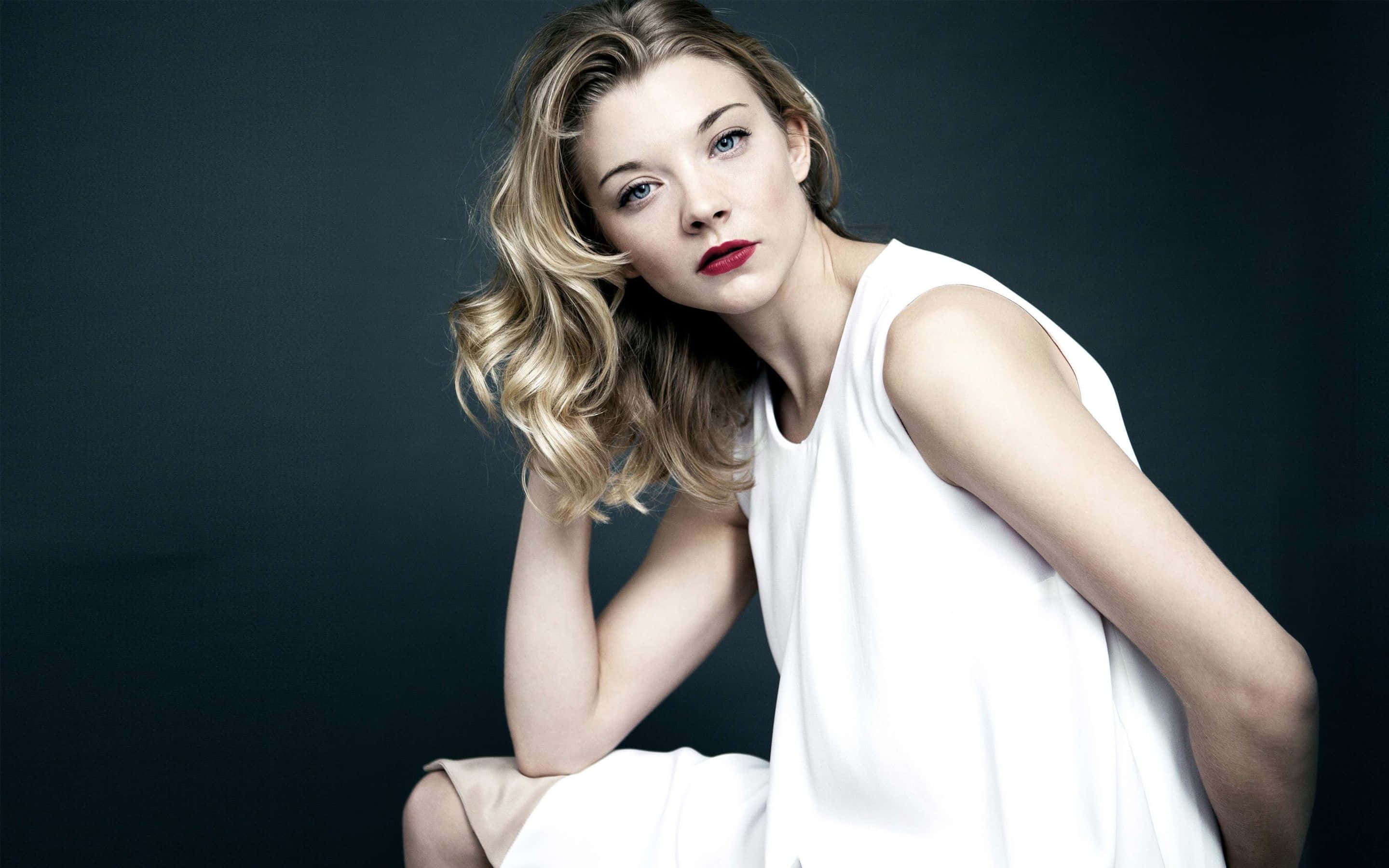 natalie dormer 桌布 壁紙 — 一位金髮女子穿著白色連衣裙，在深色攝影棚背景下以紅唇擺姿勢。