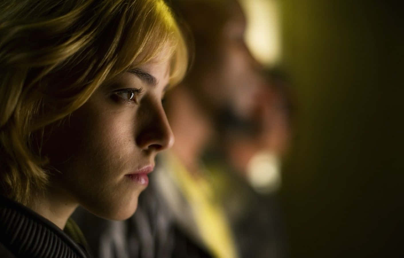 Olivia Thirlby 桌布 壁紙 — 一位金髮女性在溫暖的金色光線下，以模糊的背景側面沉思地凝視。