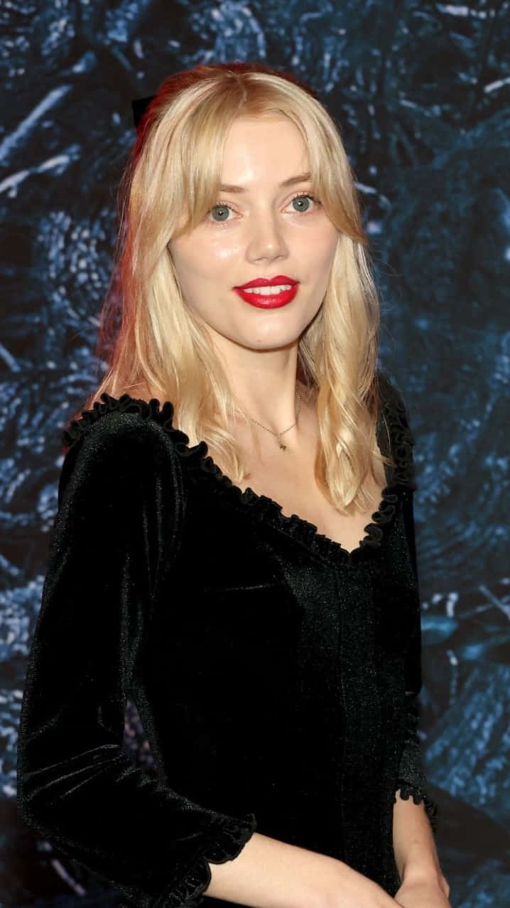 Grace Van Dien 桌布 壁紙 — 一位金髮女郎塗著紅色唇膏，穿著黑色天鵝絨上衣，背景是深色紋理。