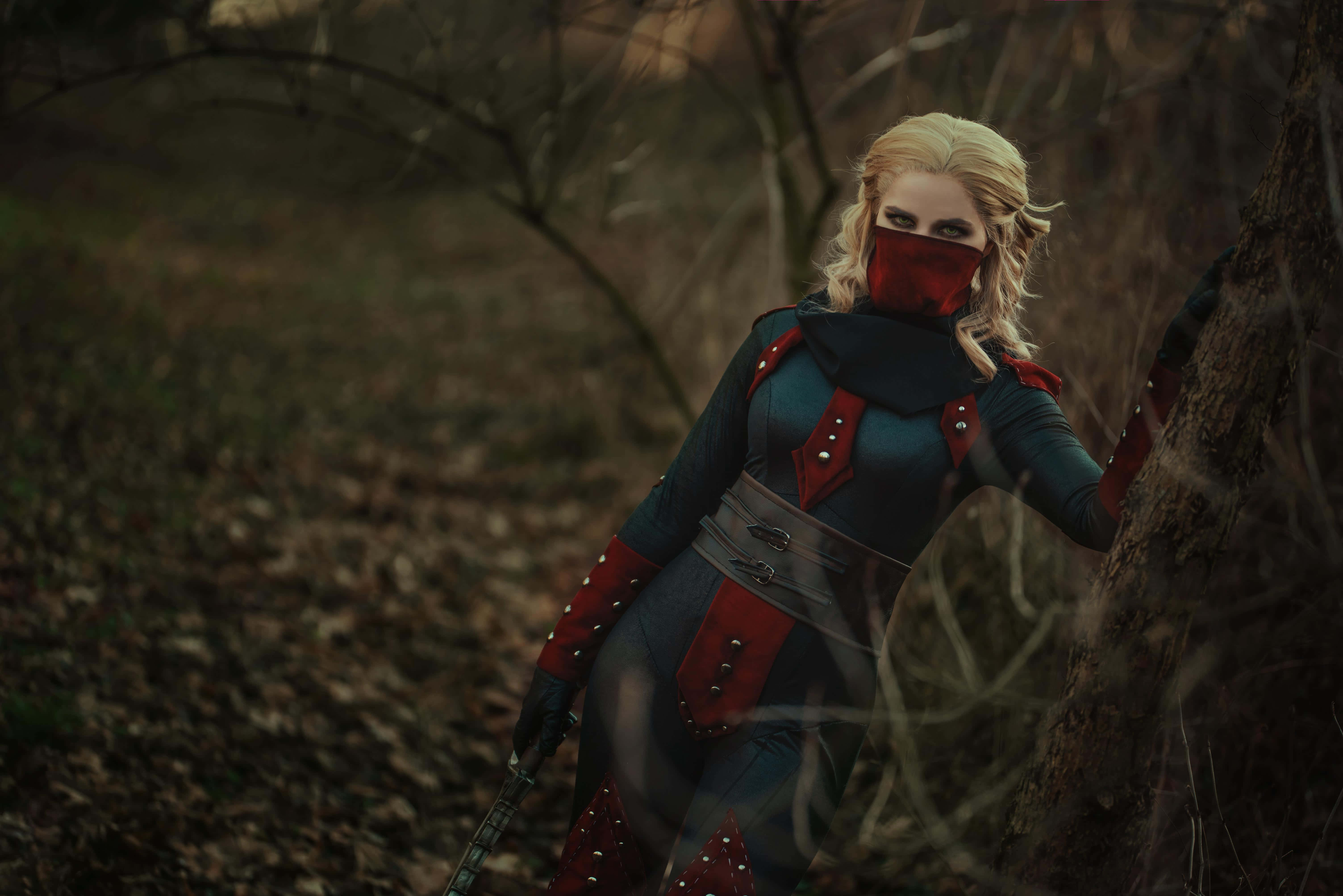 Skyrim Astrid 桌布 壁紙 — 一位金髮戰士身穿紅藍盔甲，在迷霧森林中靠著樹，手持劍。