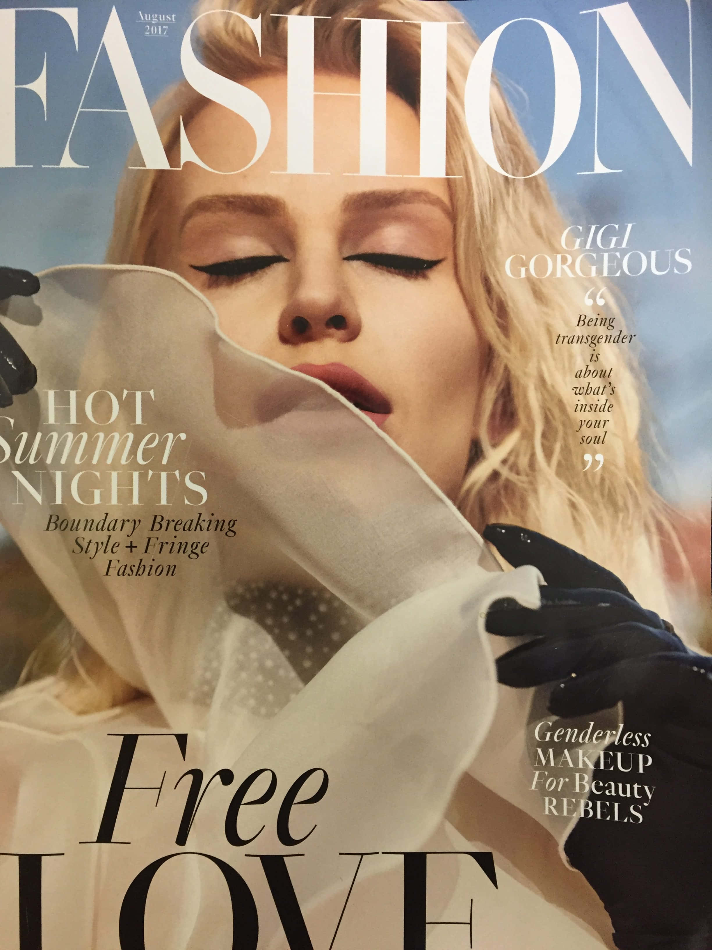 Magazine 桌布 壁紙 — 一位金髮模特兒閉上眼睛，畫著大膽眼線，戴著黑色手套，手持半透明白色布料，背景是明亮的藍天。