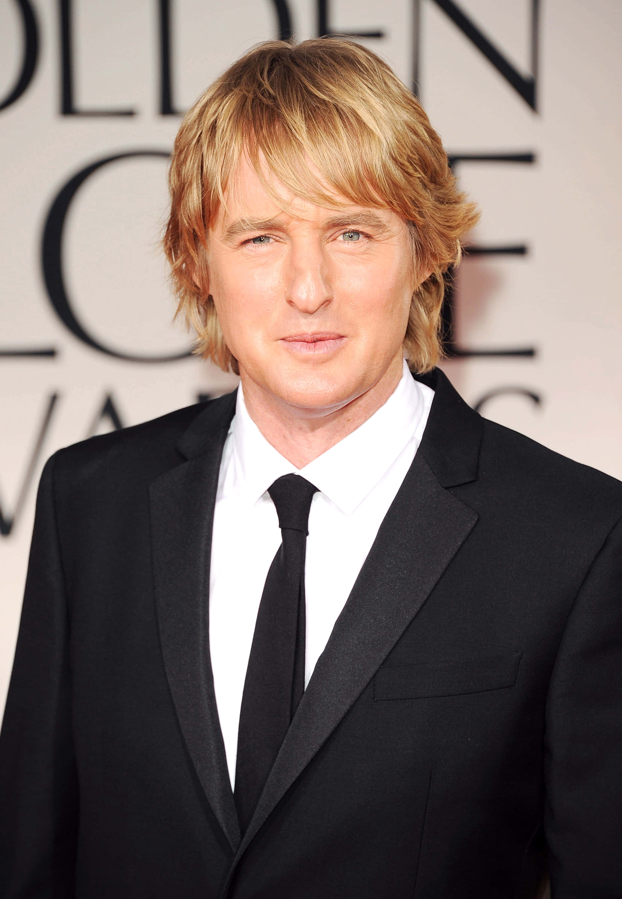Owen Wilson 桌布 壁紙 — 一位金髮男子身穿黑色西裝打領帶，在金球獎紅地毯上擺姿勢。