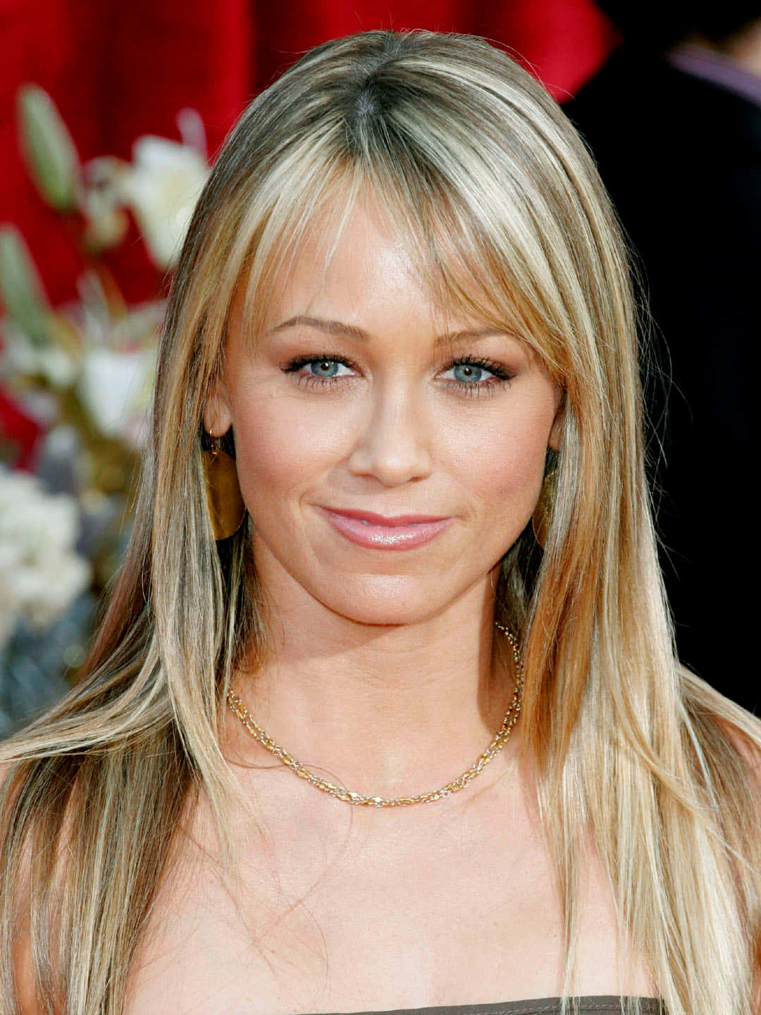 Christine Taylor 桌布 壁紙 — 一位金髮碧眼的女人在紅色背景前微笑的特寫肖像。