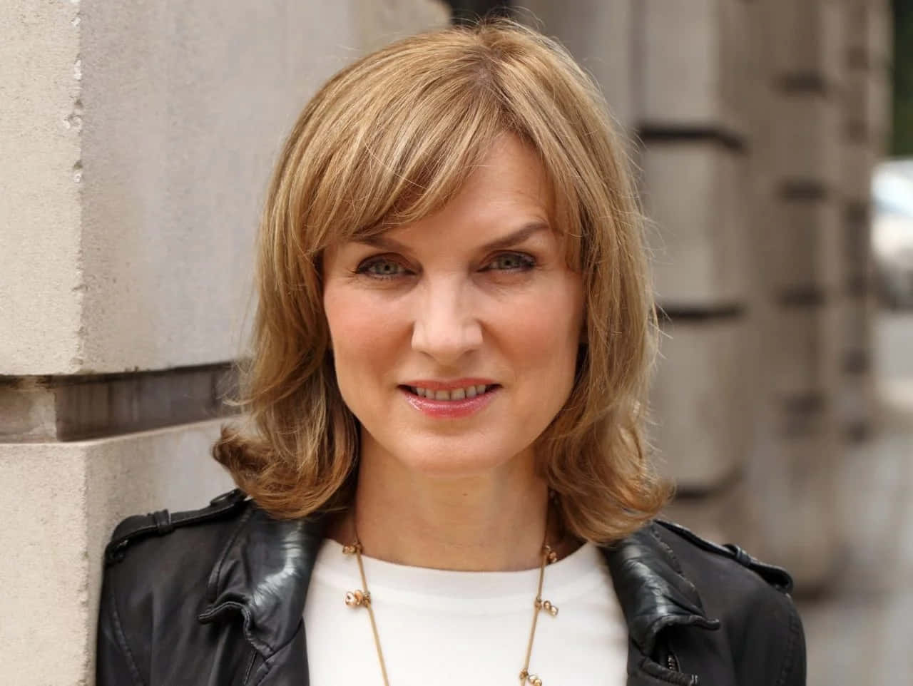 Fiona Bruce 桌布 壁紙 — 一位金髮碧眼的女士在白天靠著石頭建築微笑。
