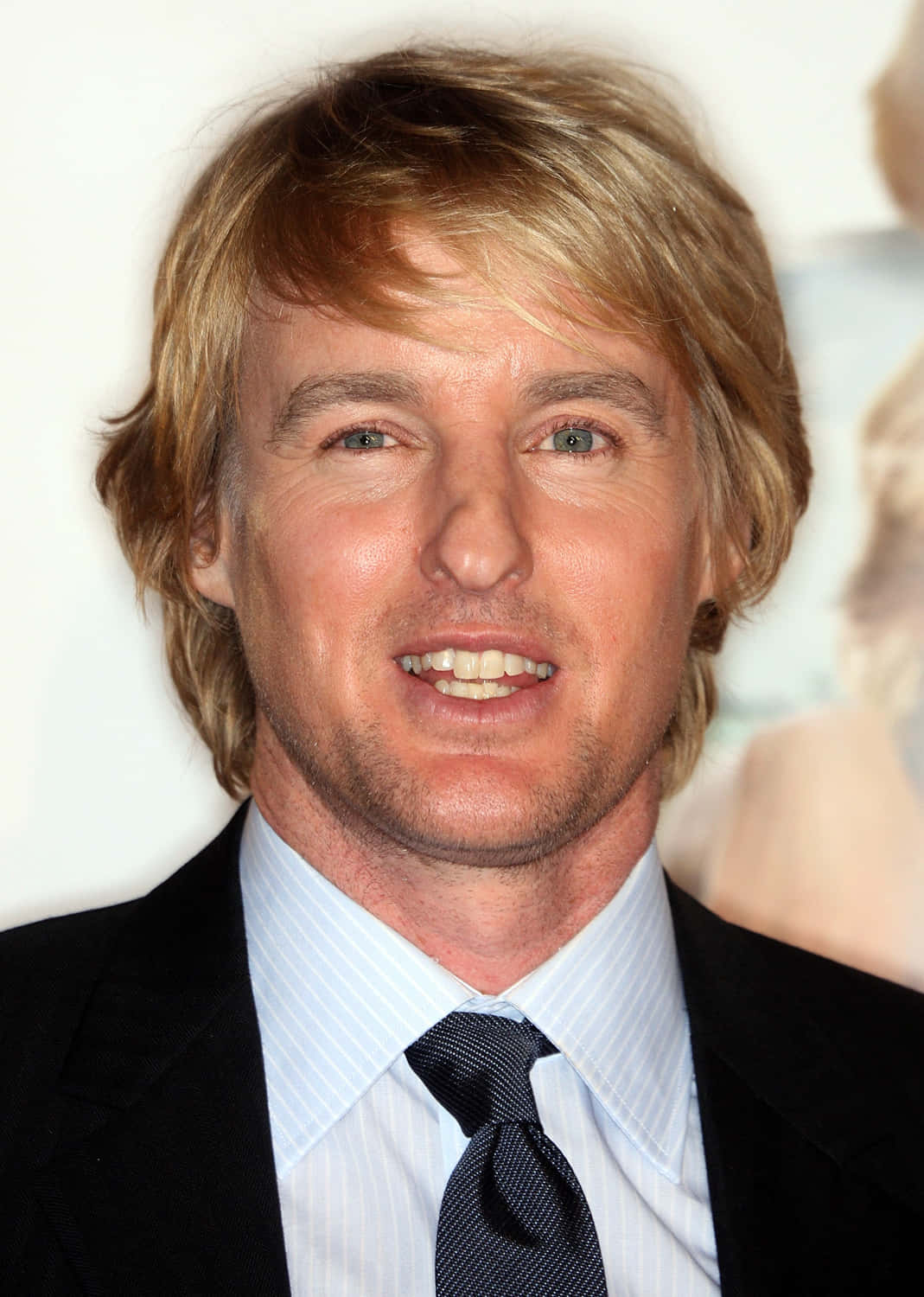Owen Wilson 桌布 壁紙 — 一位金髮綠眼男士穿著黑色西裝和條紋襯衫的特寫肖像。
