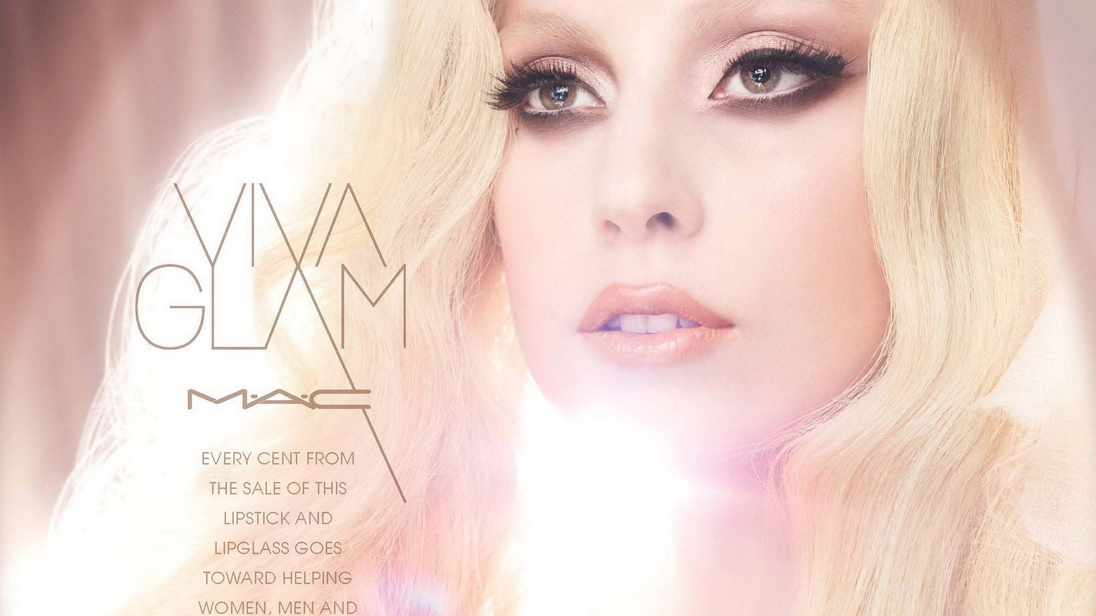 Mac Cosmetics x Lady Gaga 壁紙 — 一位金髮美女的迷人特寫，煙燻眼妝和柔和粉唇，襯托著耀眼的光線背景。
