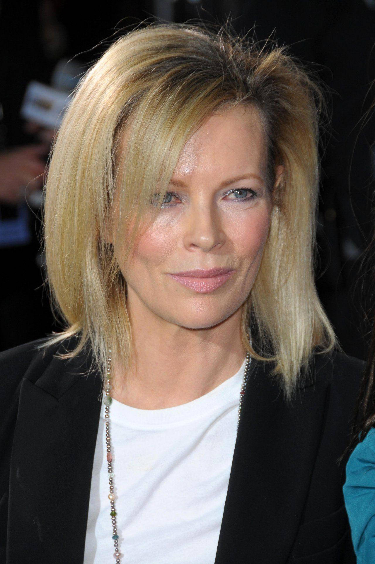 "Kim Basinger at Twilight Premiere 2008" 壁紙 — 一位金髮藍眼女子的特寫肖像，身穿黑色西裝外套內搭白色T恤，佩戴珠串項鍊。