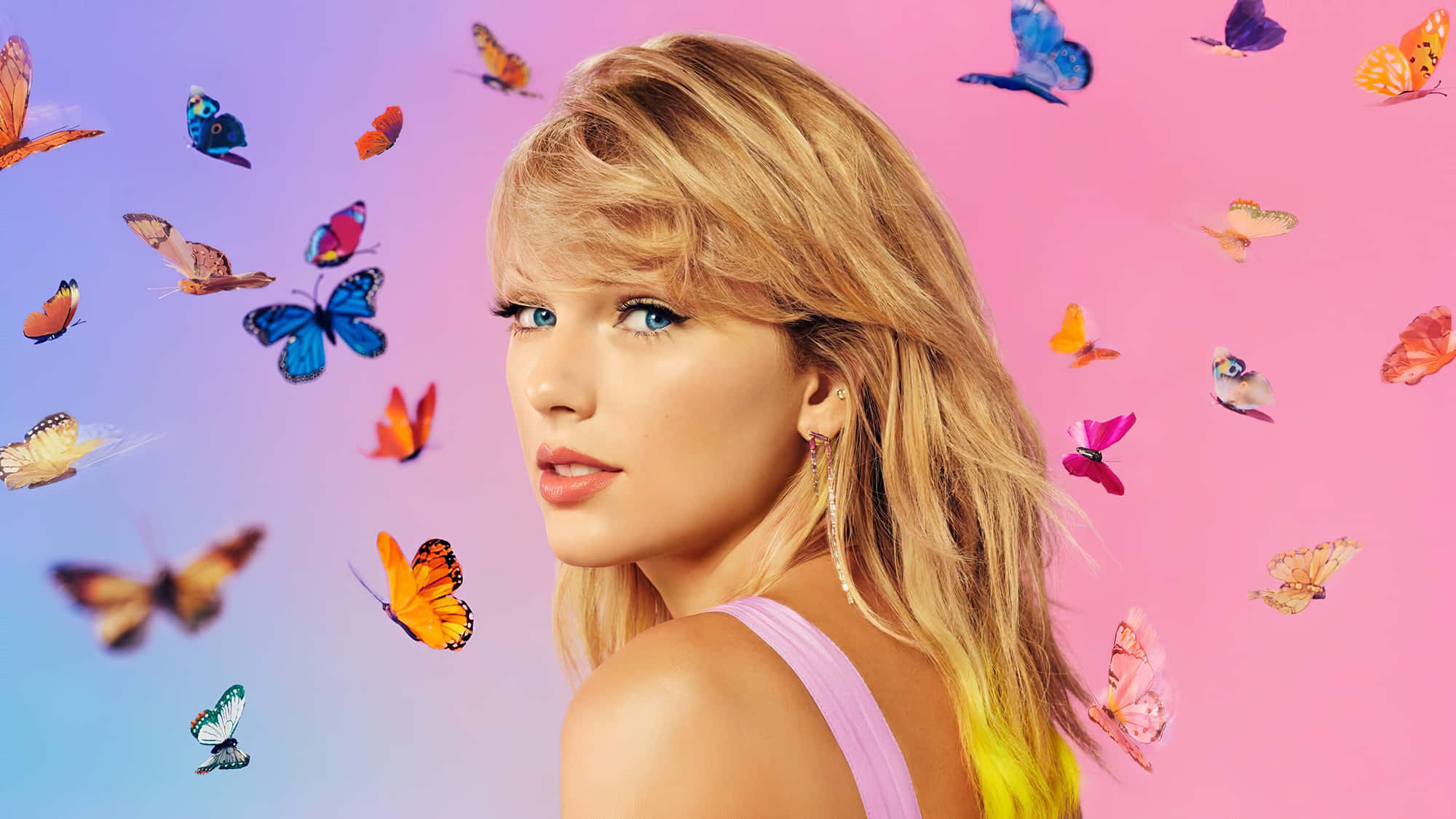 Taylor Swift 桌布 壁紙 — 一位金髮藍眼的女性回頭凝視，色彩繽紛的蝴蝶在她周圍翩翩起舞，背景是粉紅和藍色的漸變色。
