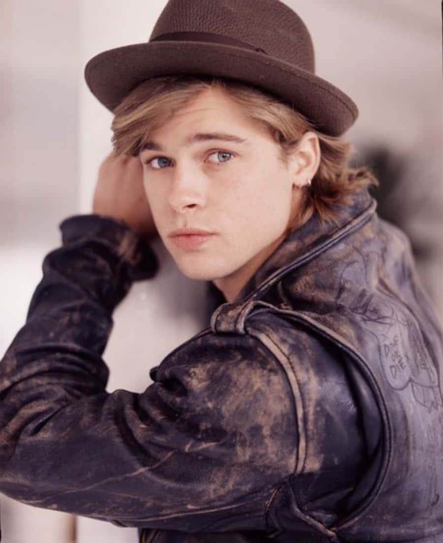 Brad Pitt 桌布 壁紙 — 一位金髮藍眼的年輕男子戴著棕色帽子，穿著破舊的皮夾克，直視鏡頭。