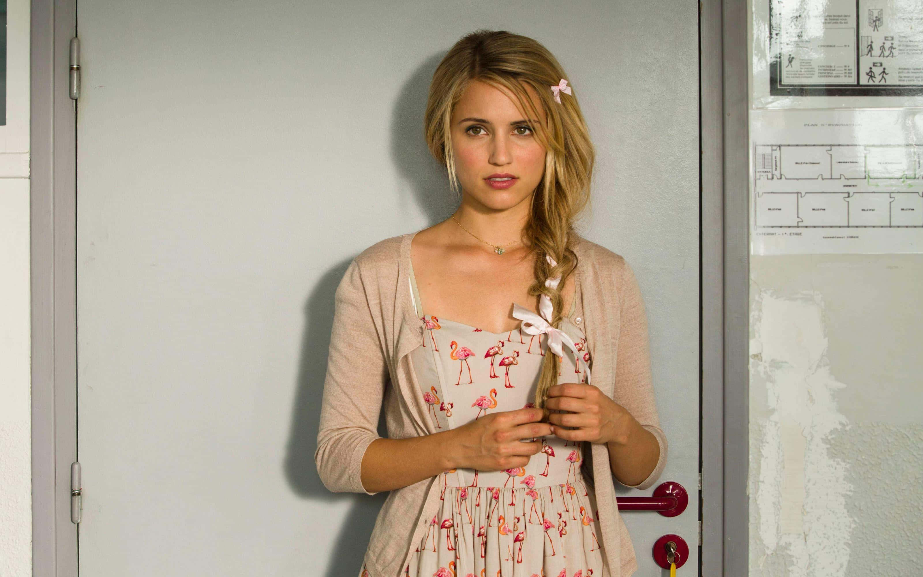 dianna agron 桌布 壁紙 — 一位金髮辮子年輕女子站在門口，身穿火烈鳥印花連衣裙和米色開襟衫。
