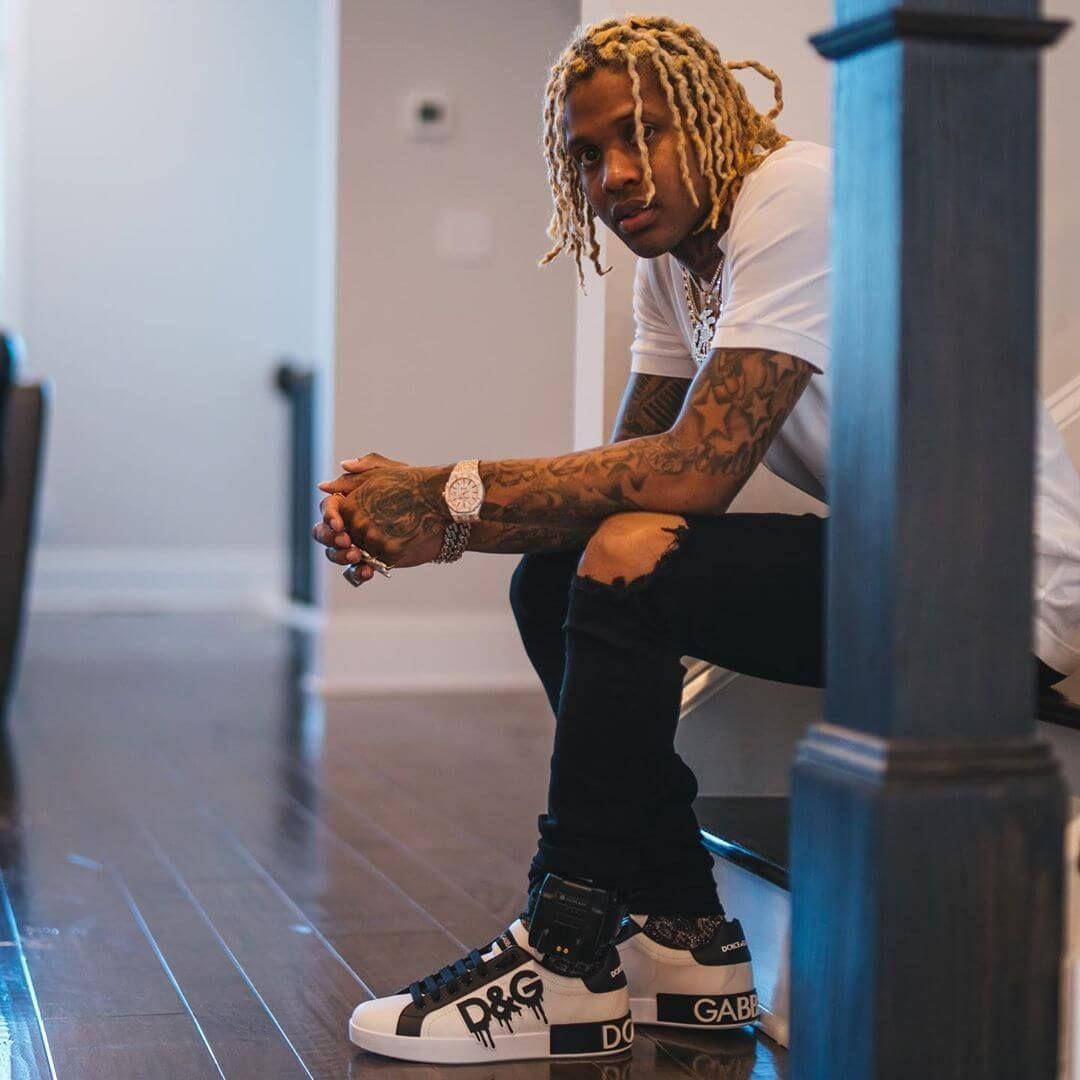 King Von And Lil Durk 桌布 壁紙 — 一位金髮辮子紋身年輕男子坐在樓梯上，穿著品牌運動鞋和白色T恤。