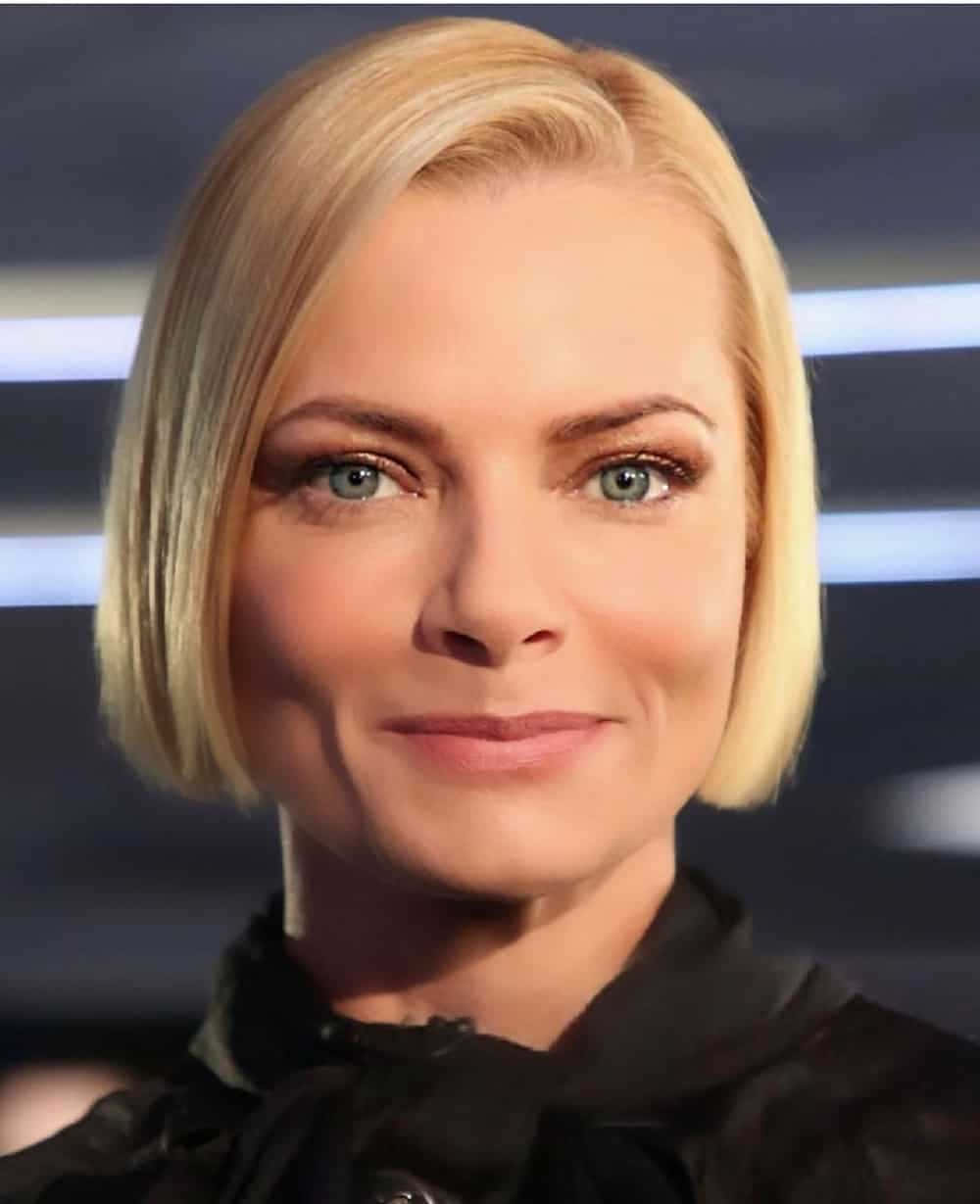 Jaime Pressly 桌布 壁紙 — 一位金髮鮑伯頭、藍眼睛的女性在模糊的未來背景前微笑的特寫肖像。