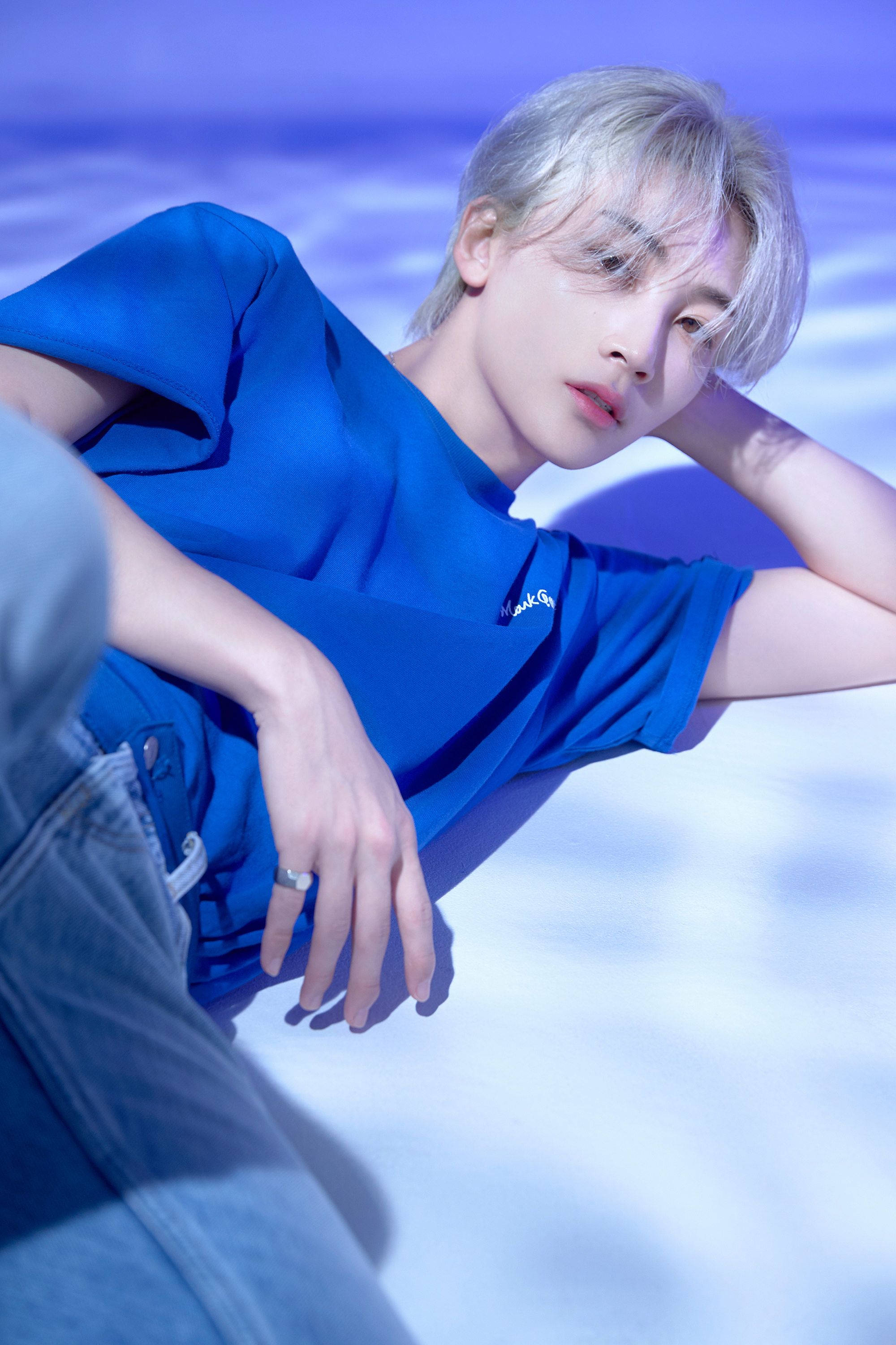 Yoon Jeonghan HIT 壁紙 — 一位銀髮年輕人身穿藍色襯衫，在柔和的藍白漸變背景上放鬆。