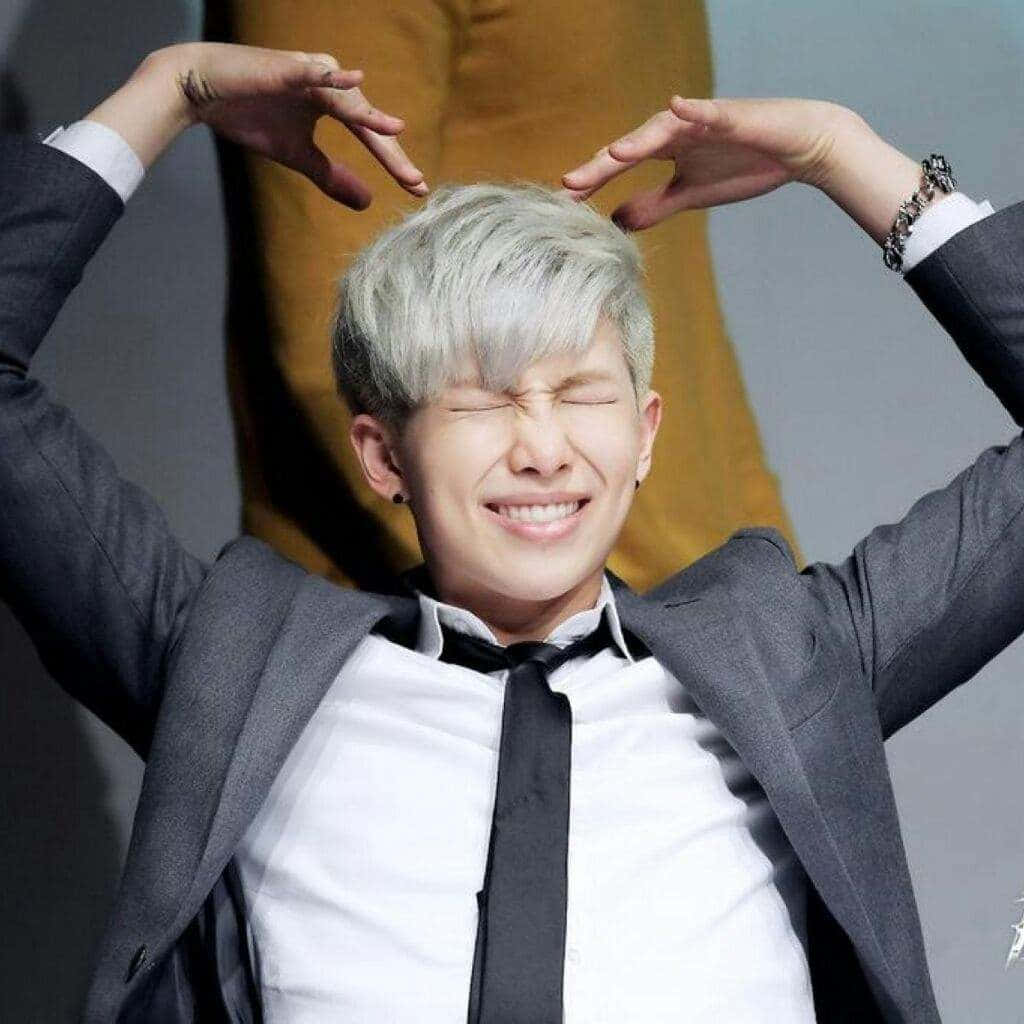 Bts Rap Monster 桌布 壁紙 — 一位銀髮年輕男子閉著眼睛，雙手在頭頂比出心形，咧嘴大笑。