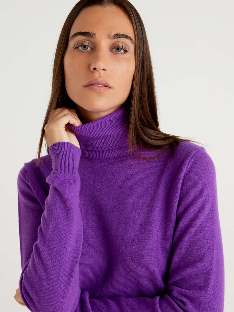 Purple Turtle-neck Sweater 桌布 壁紙 — 一位長棕色頭髮的女性，在純白色背景前穿著一件充滿活力的紫色高領毛衣。