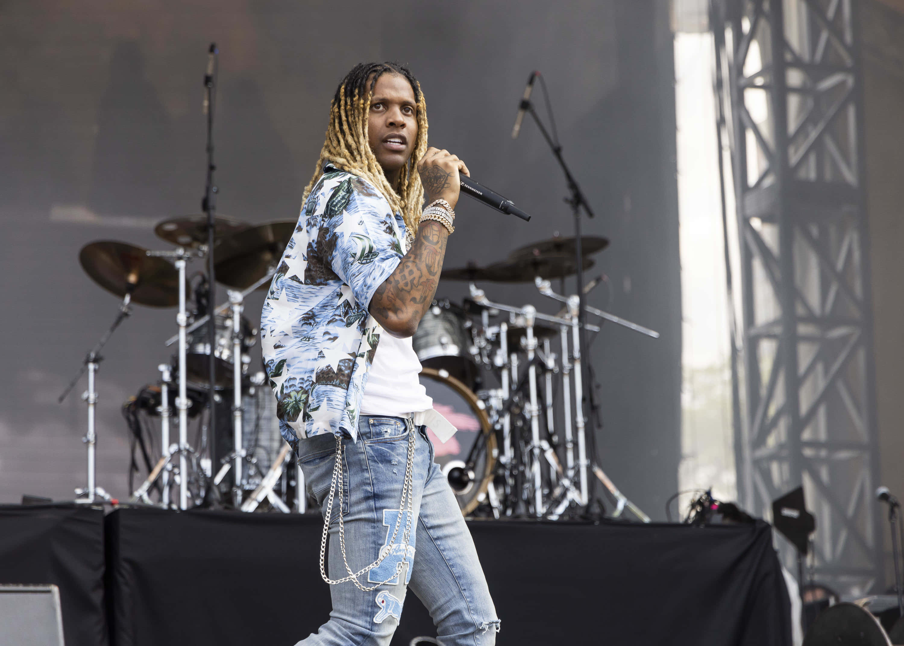 lil durk 桌布 壁紙 — 一位長辮子的男饒舌歌手在舞台上拿著麥克風表演，身後有鼓組。
