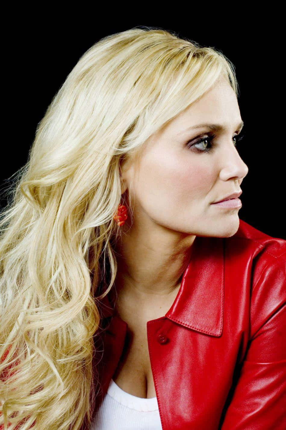 kristin chenoweth 桌布 壁紙 — 一位長金髮的女性在黑色背景前穿著紅色皮夾克。