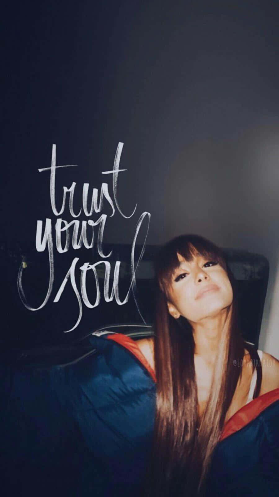 Aesthetic Ariana Grande 桌布 壁紙 — 一位長長棕色頭髮的女性在深色背景上，優雅的白色草書文字「trust your soul」旁邊向上凝視。
