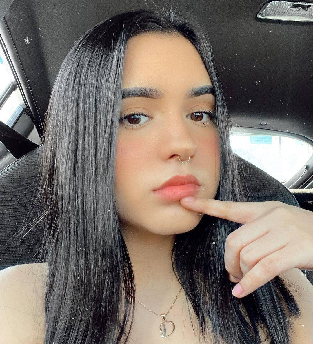 黑髮年輕女性坐在車內觸碰嘴唇。 — TikTok GIF 壁紙
