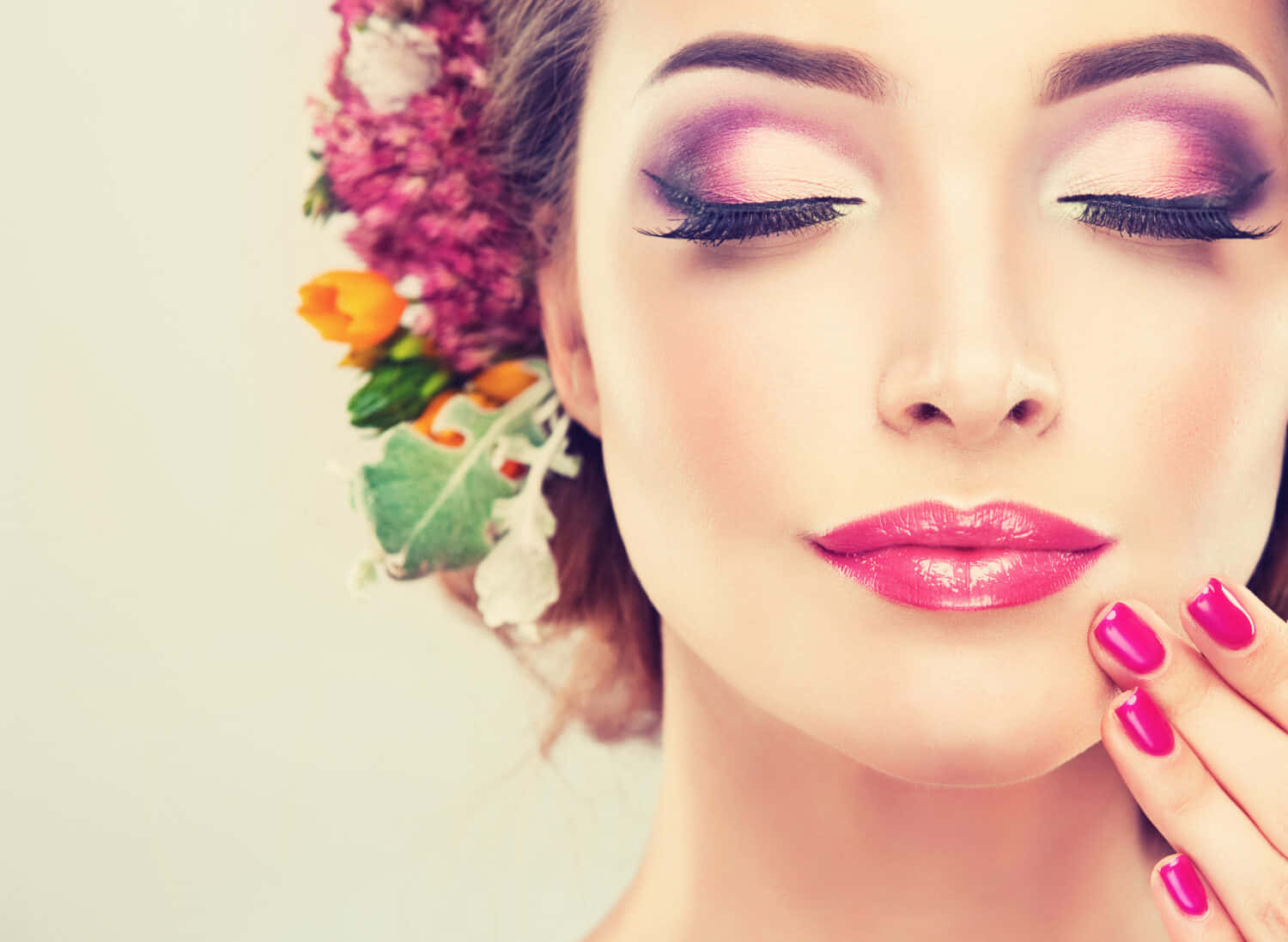 Spring Makeup 桌布 壁紙 — 一位閉上眼睛、化著鮮豔粉紅妝容、戴著色彩繽紛花冠的女性，輕輕觸碰她的臉頰。