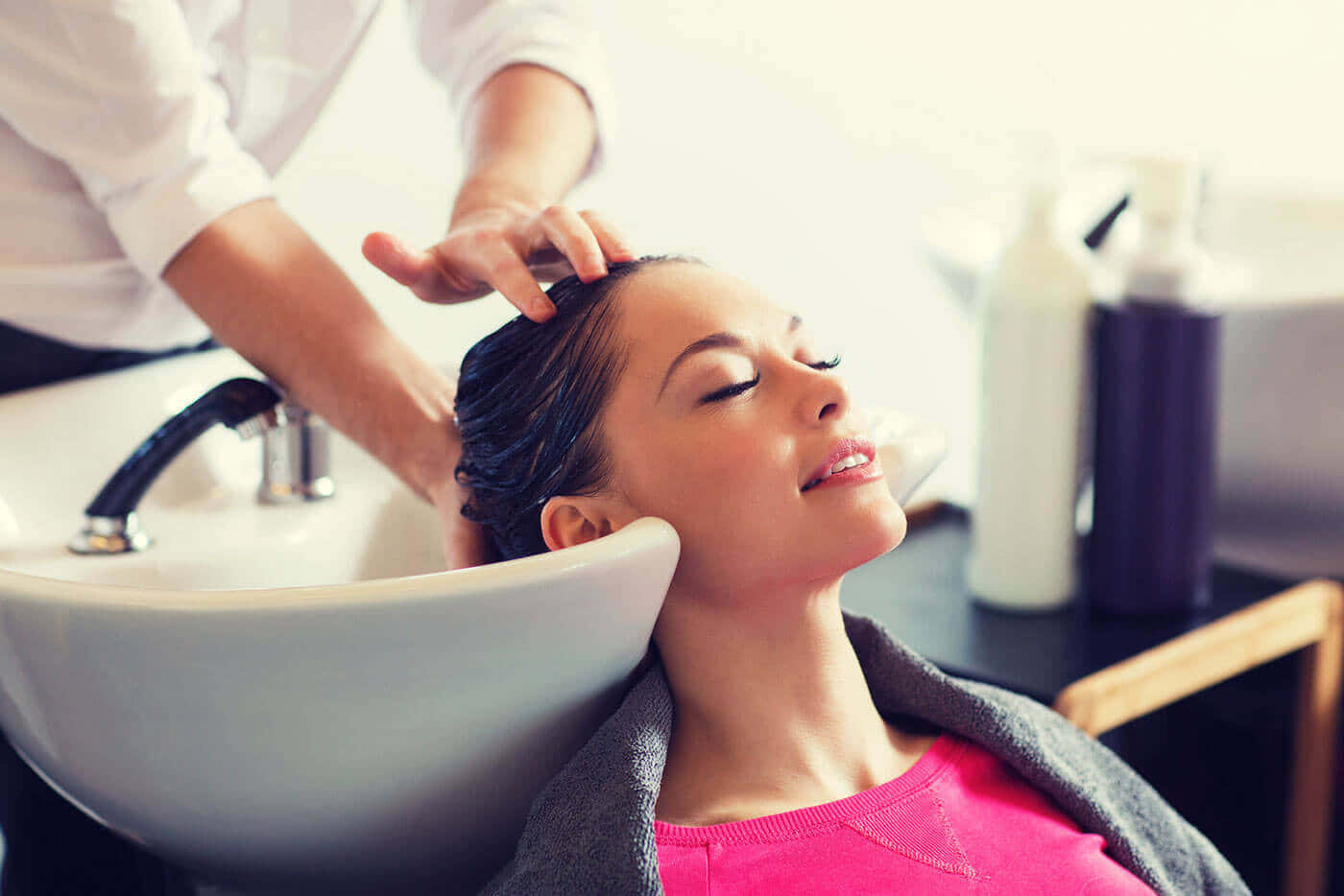 Beauty Salon 桌布 壁紙 — 一位閉著眼睛的女性，在沙龍水槽中享受造型師按摩她濕髮的同時，平靜地微笑。