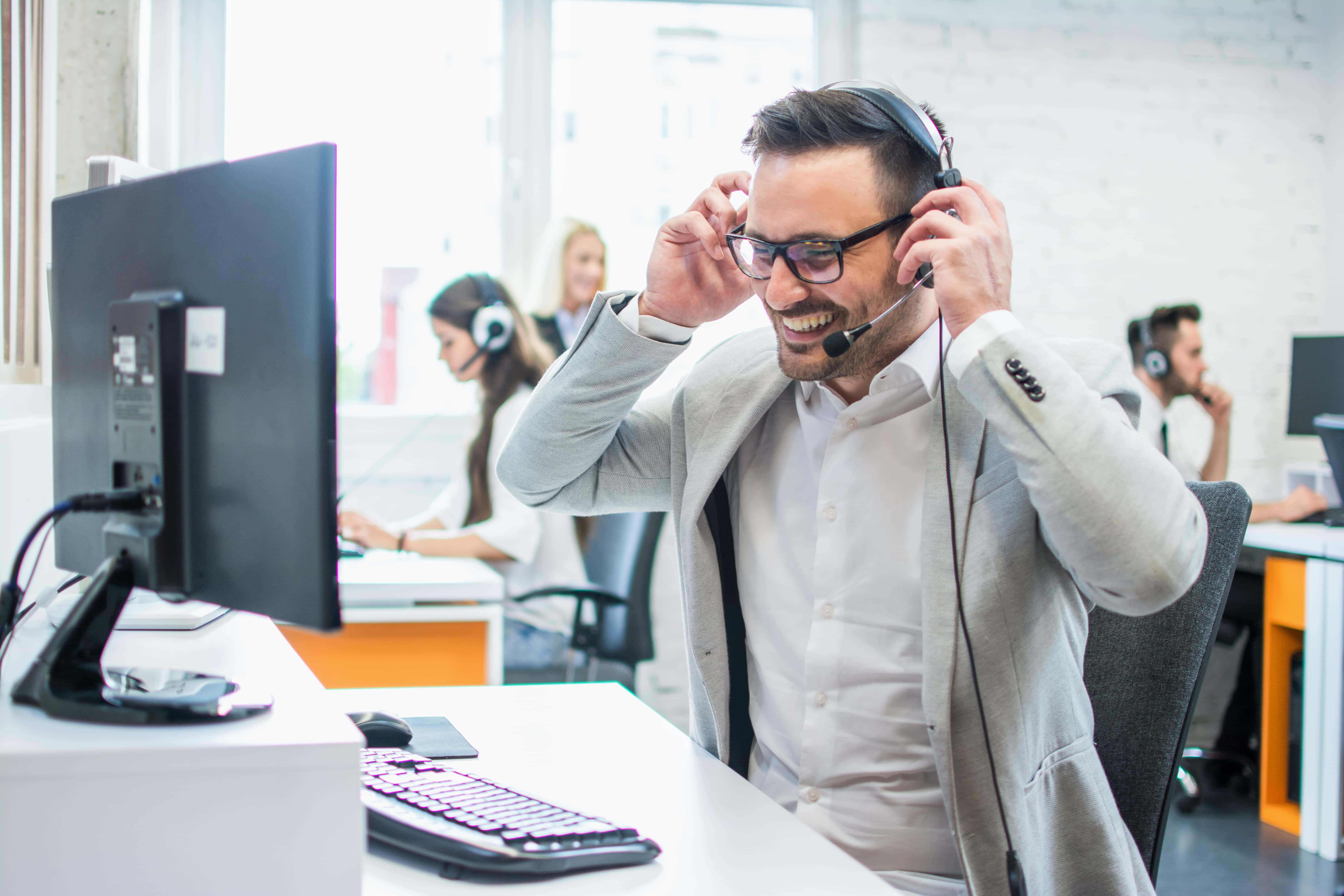 Telemarketing 桌布 壁紙 — 一位開心的客戶服務專員在明亮現代辦公桌上調整耳機時大笑。